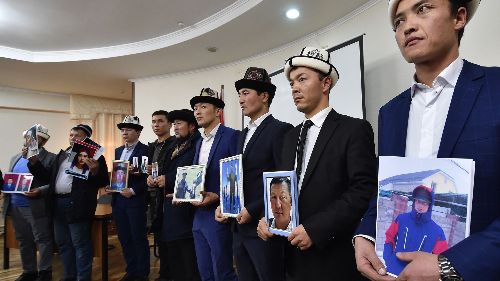 Photo of relatives holding pictures of Kyrgyz men who've "disappeared" into re-education camps