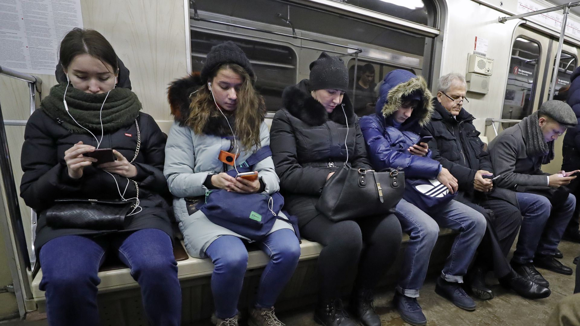 люди с телефонами в метро