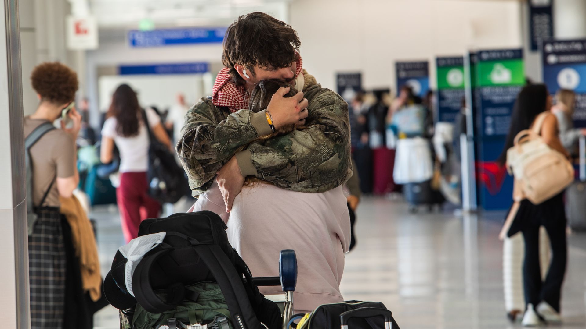 Travelers hug each other in the departure terminal at the Los Angeles International Airport (LAX)