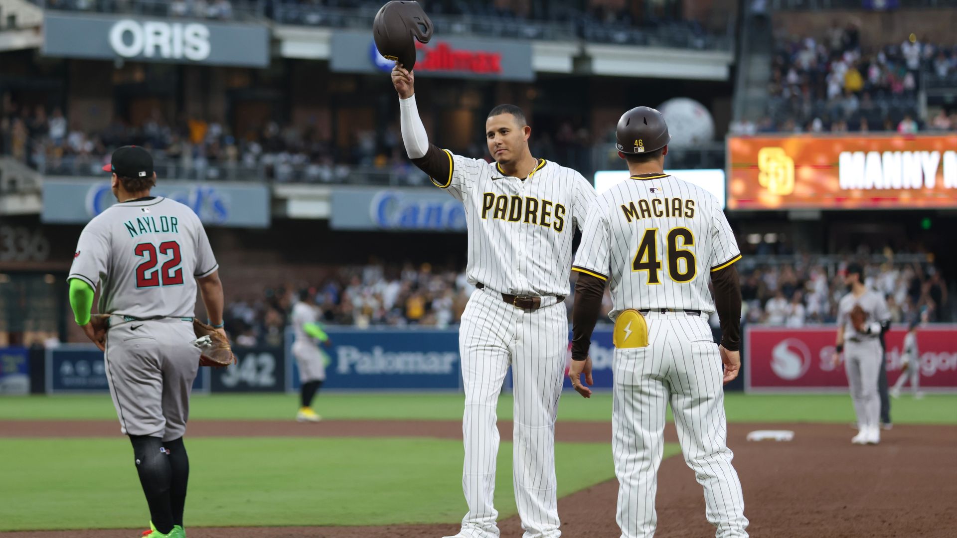 Manny Machado tips his cap to fans standing on first base