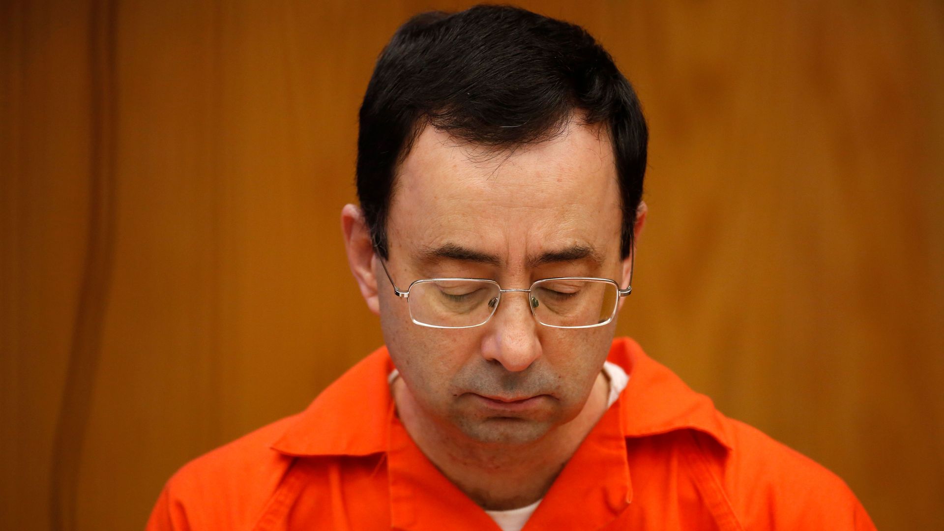 Photo of Larry Nassar in an orange jumpsuit looking down