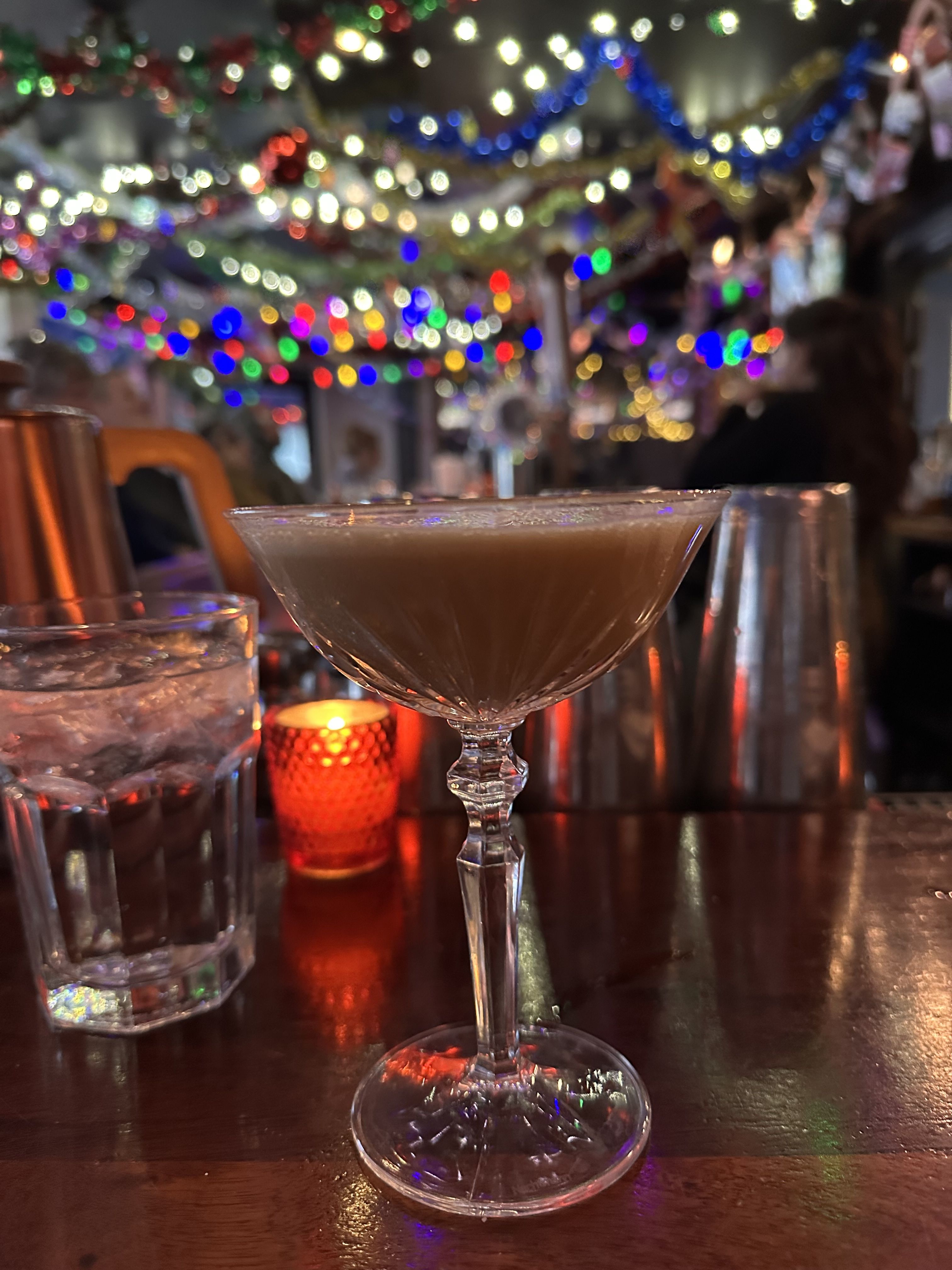 an espresso martini surrounded by holiday lights 