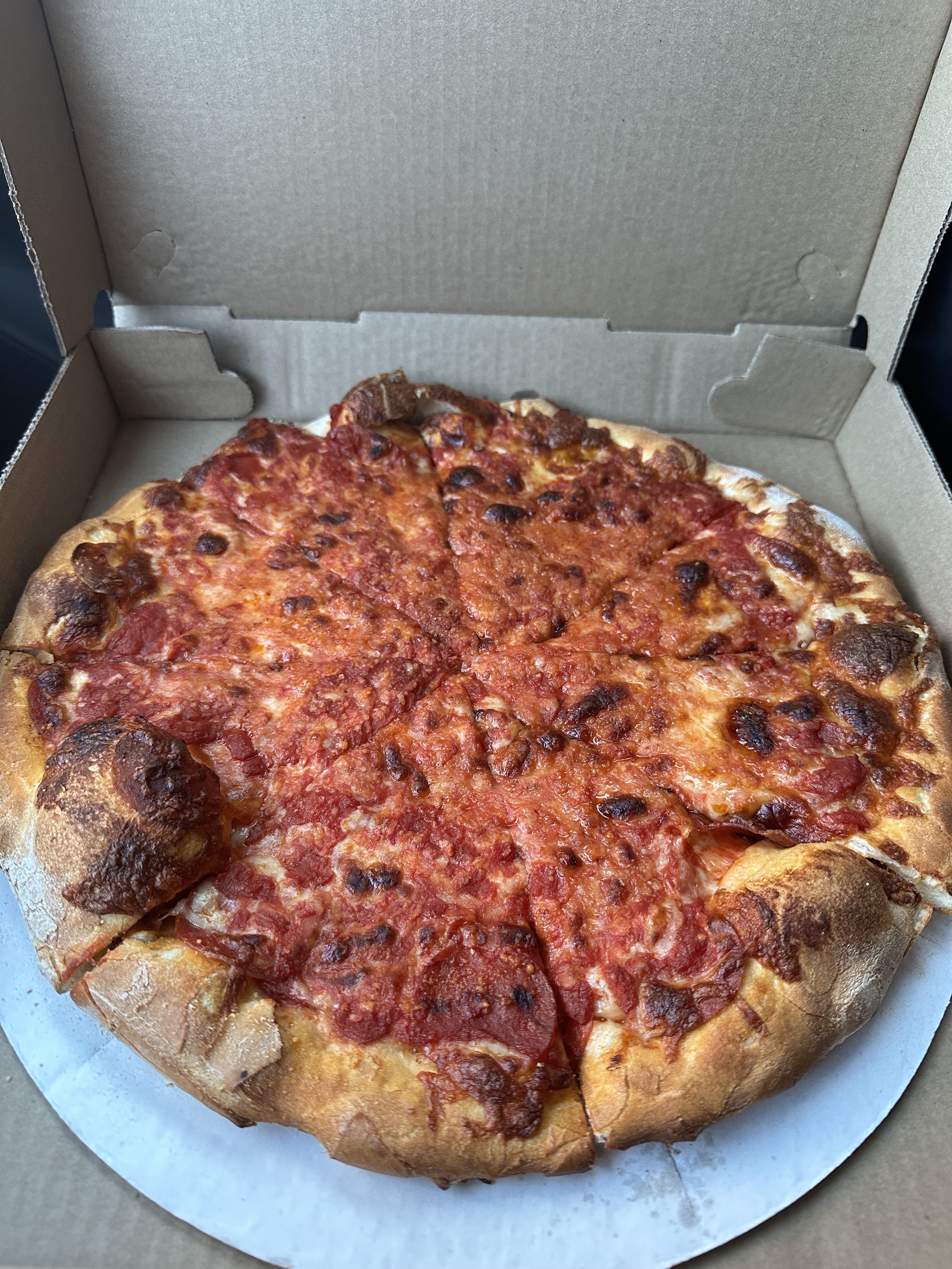 A burnt pie of pepperoni pizza that appears to have one or two pepperonis on the pie from Santarpio's in East Boston. The pepperonis turned out to be hiding under the cheese.