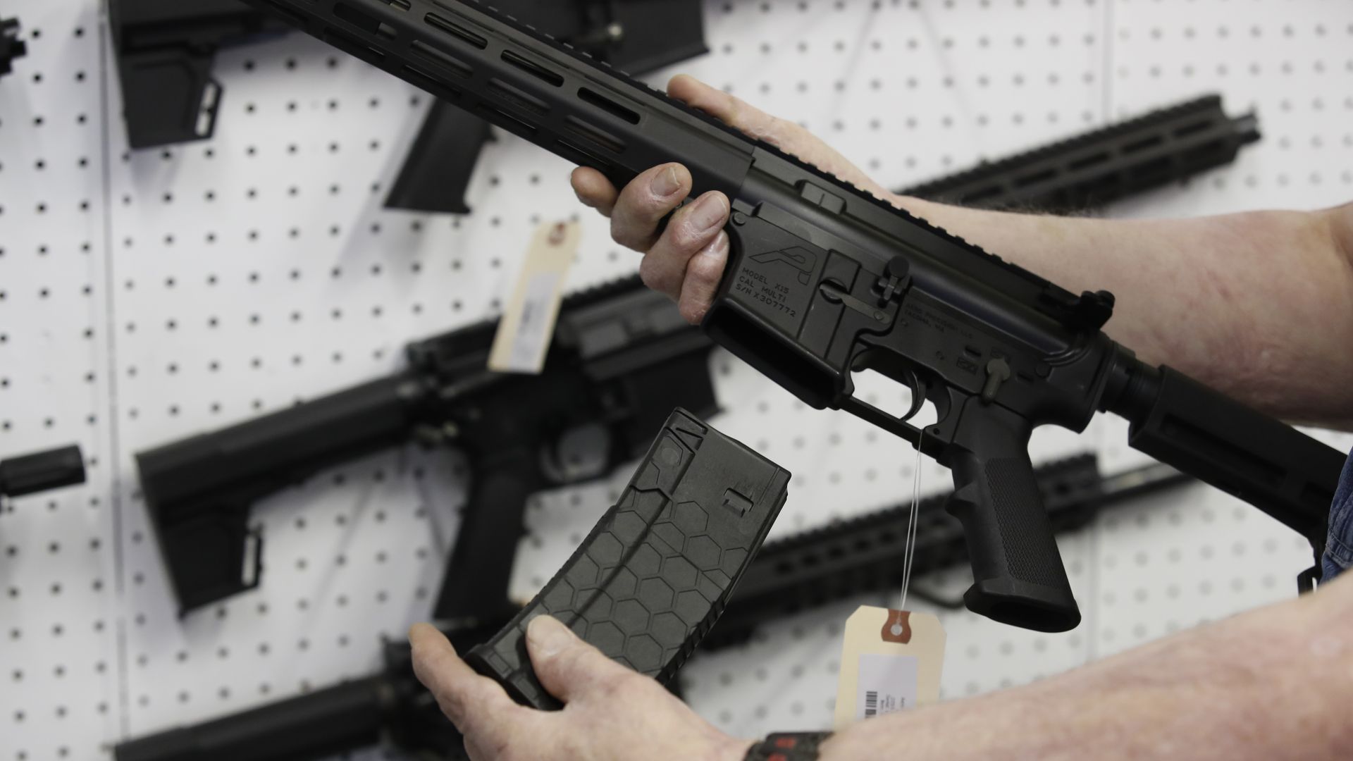 Photo of two arms holding a high-capacity magazine for an AR-15 rifle at a gun store