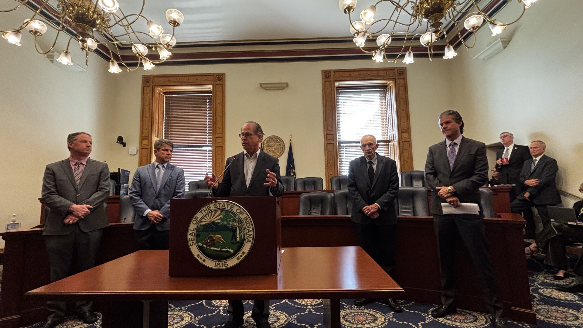 Five men standing in a room with a podium