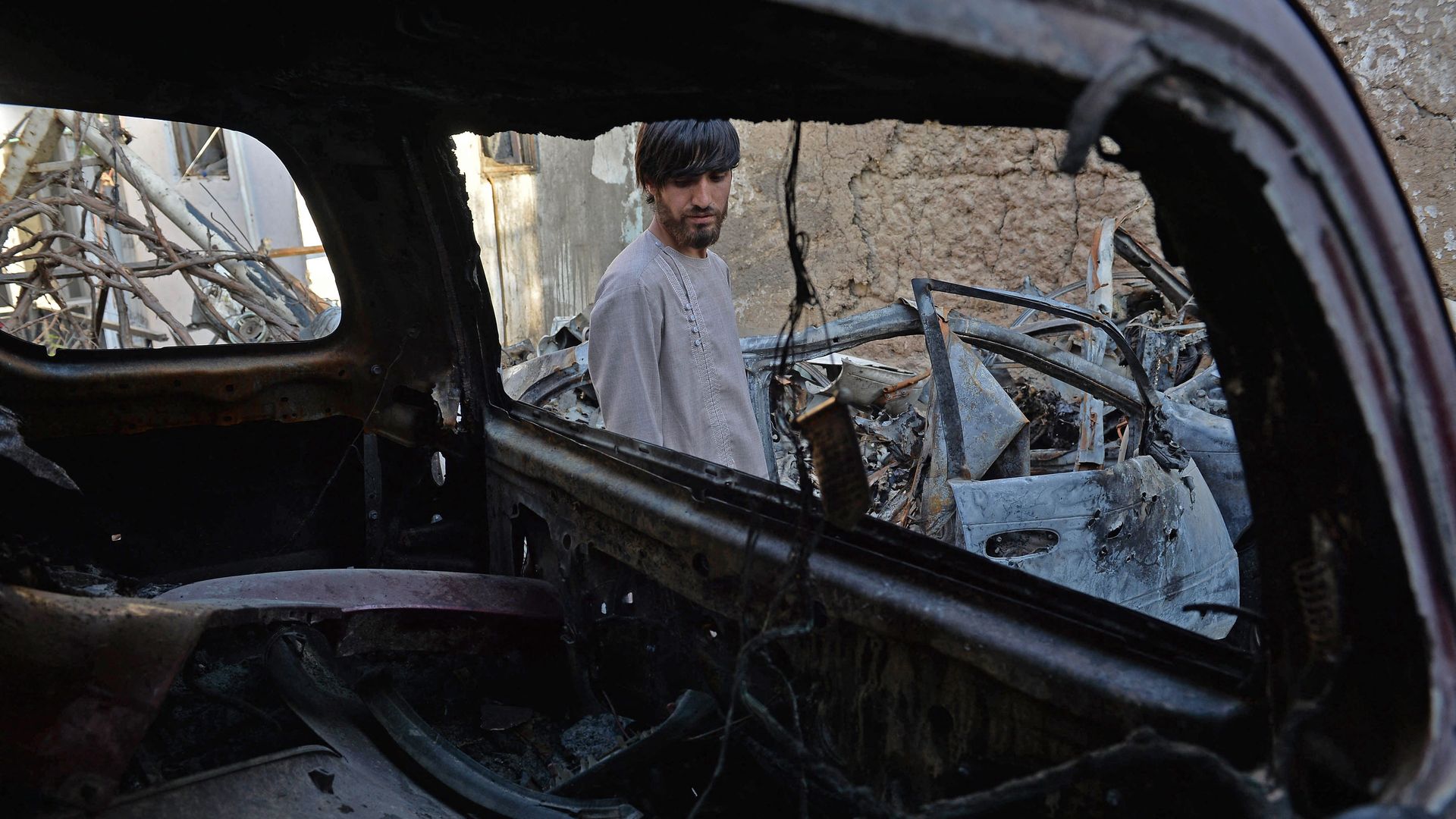 A relative of Ezmarai Ahmadi, is pictured through the wreckage of a vehicle that was damaged in a US drone strike in the Kwaja Burga neighbourhood of Kabul on September 18