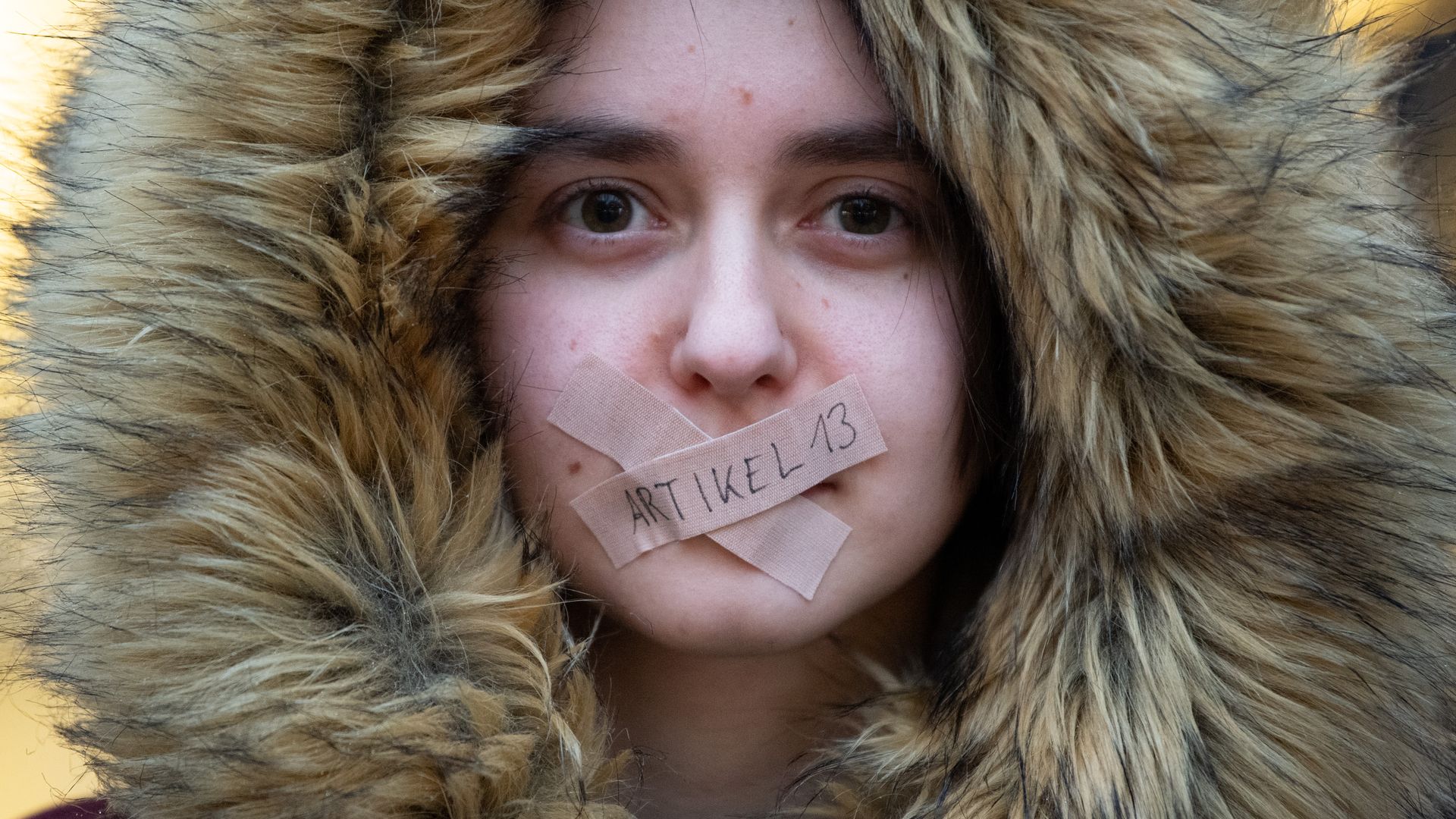 Photo of protester in Germany with tape over her mouth.