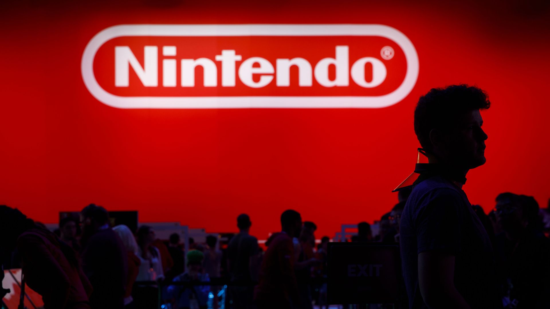 Photo of Nintendo's logo on a big red wall with people walking in front of it