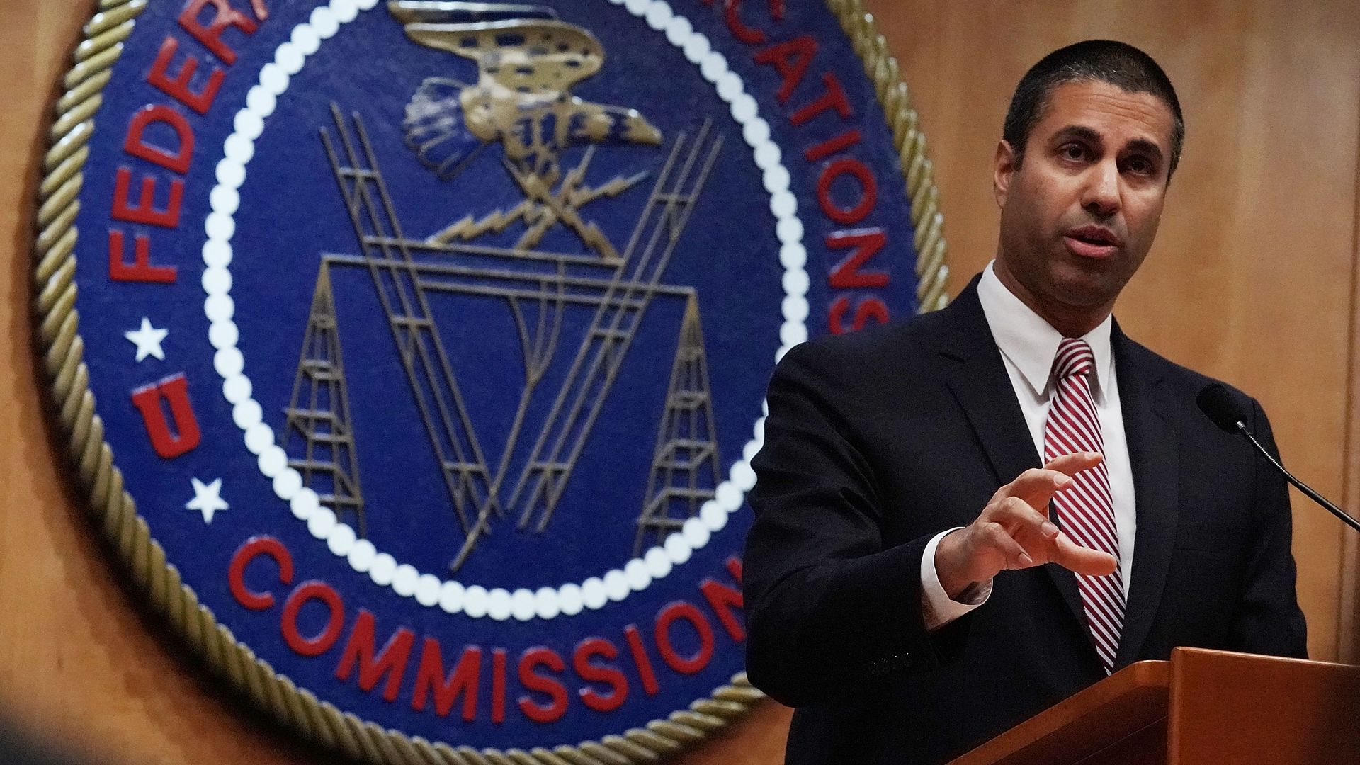 Ajit Pai standing at a podium in front of the FCC seal