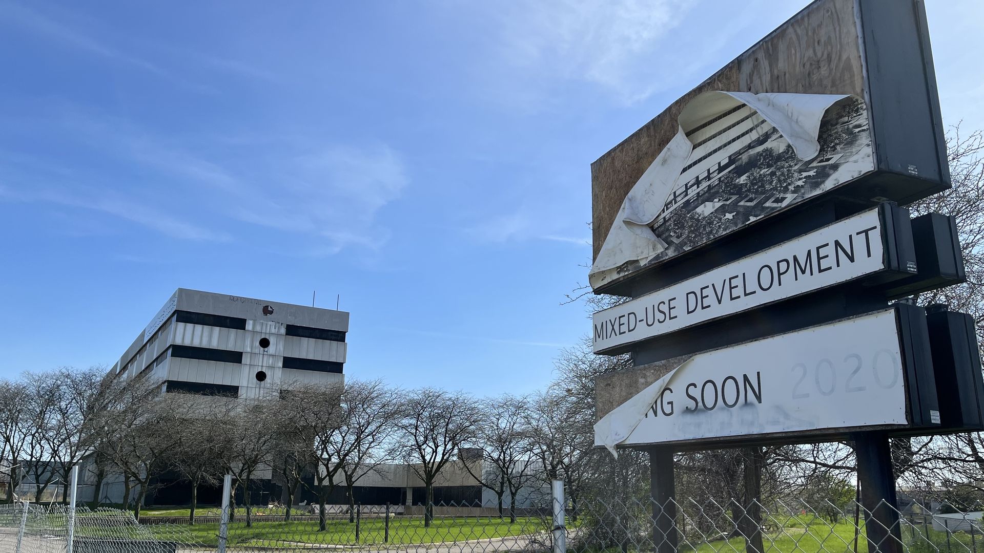The old southwest Detroit hospital building is pictured near a crumpled old sign advertising a "mixed use development."