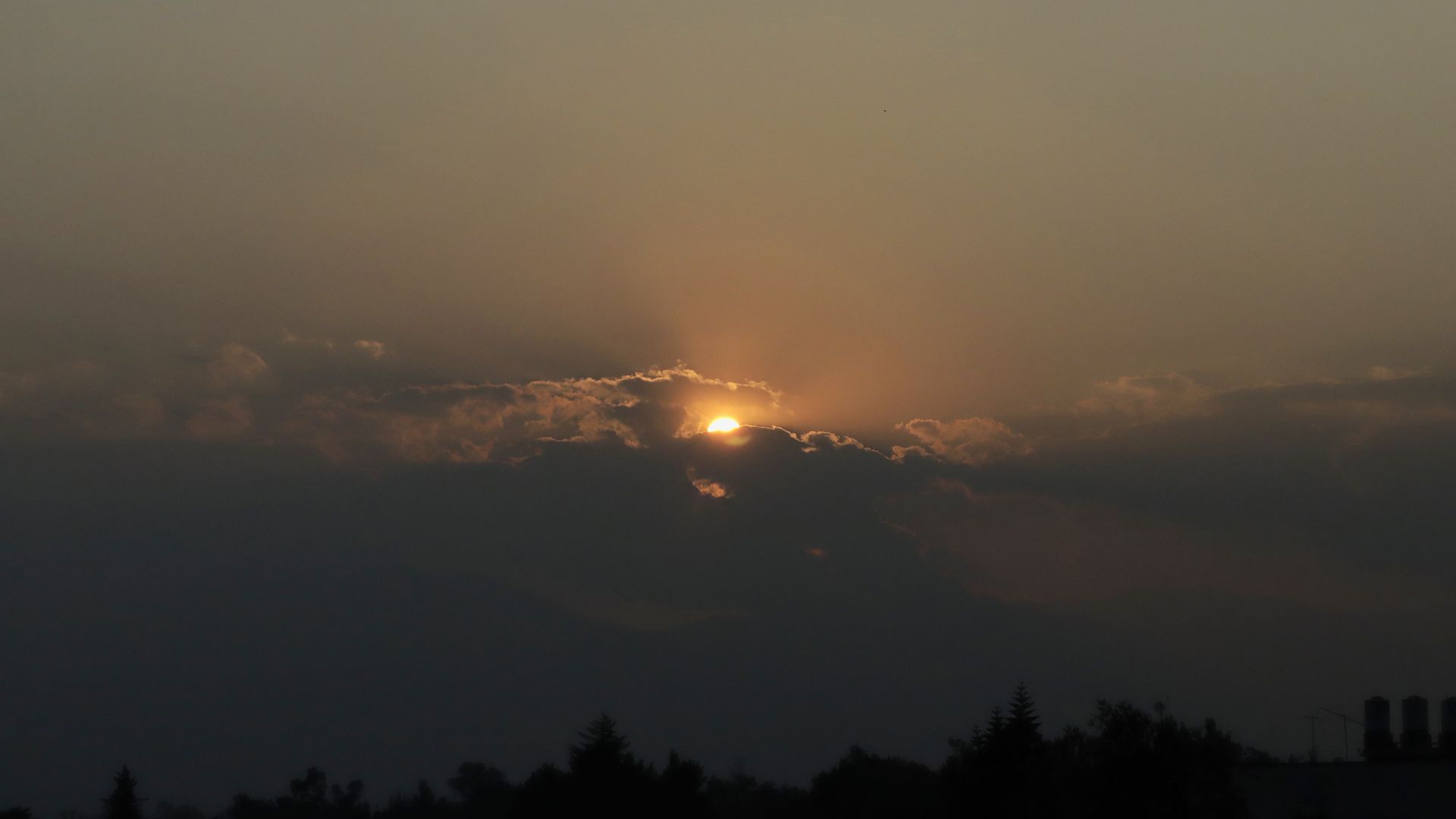 A sun sets into a cloud.