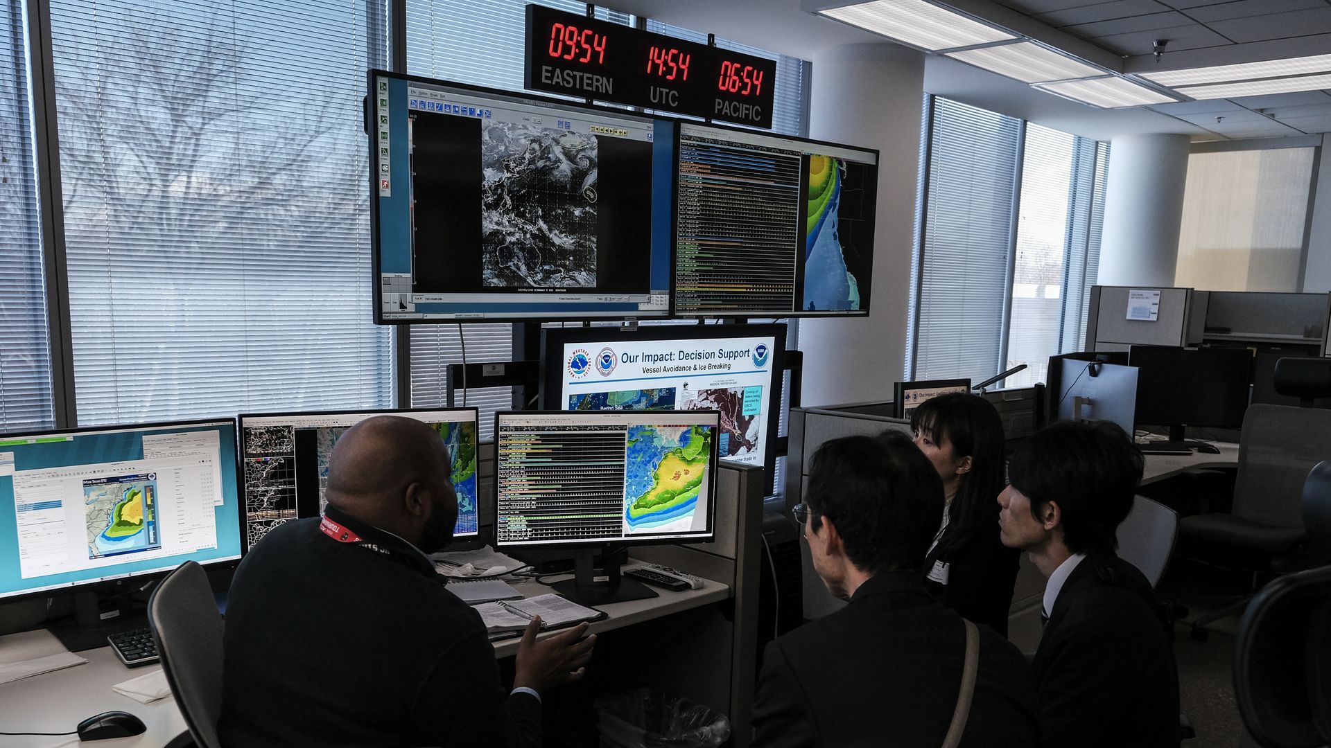 A group of people looking at weather data on computer screens.