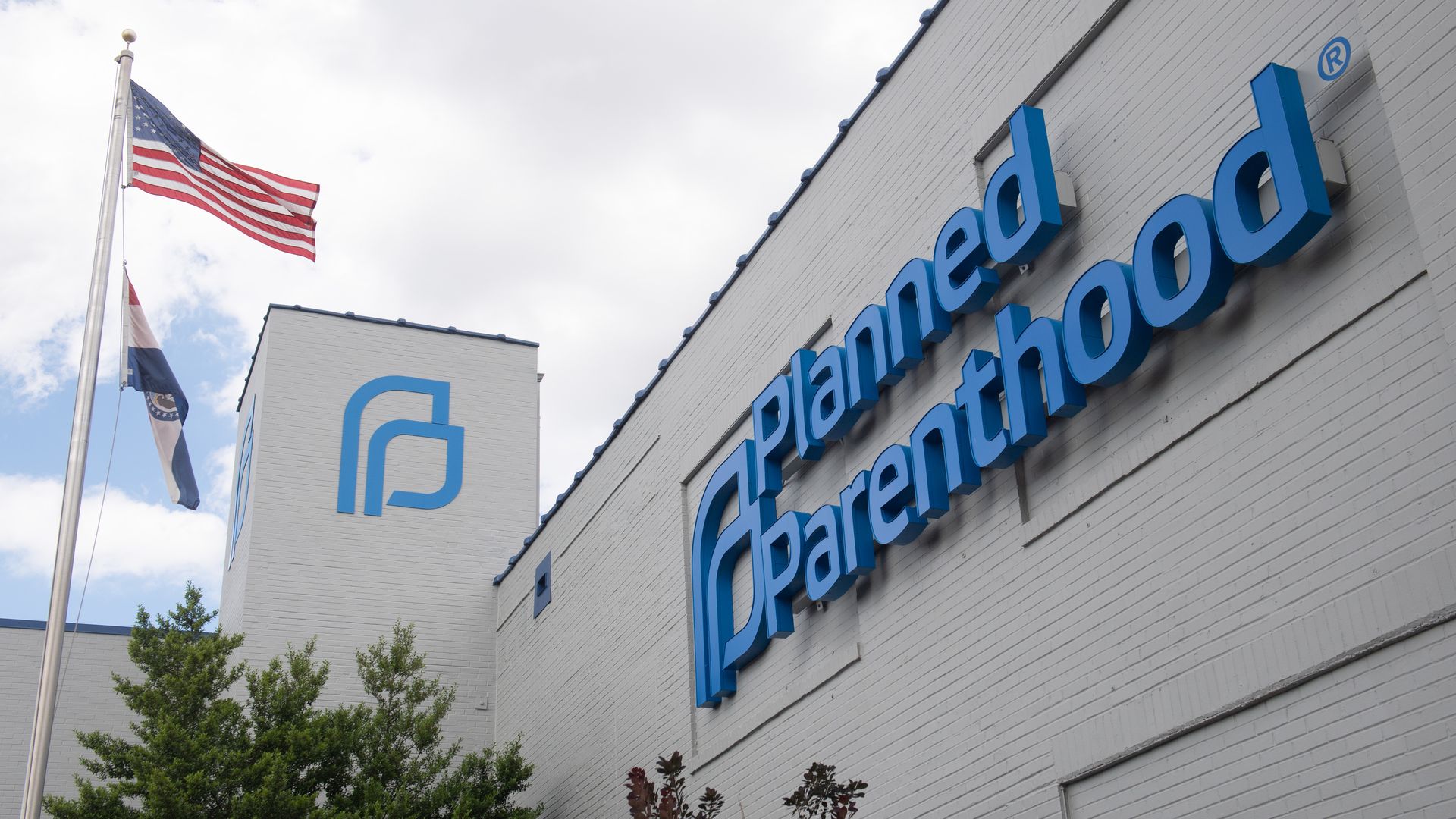Photo of the exterior of a Planned Parenthood clinic, with its logo in blue and an American flag flying on a flagpole nearby
