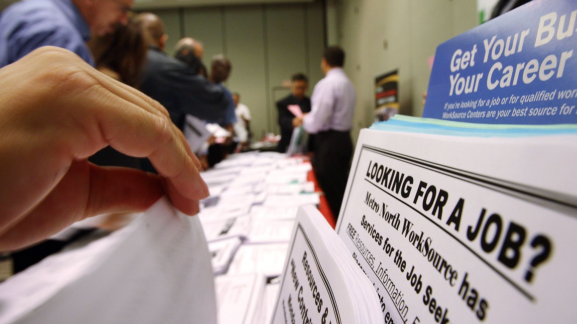 A long table with a variety of papers. The closest one reads "looking for a job?"
