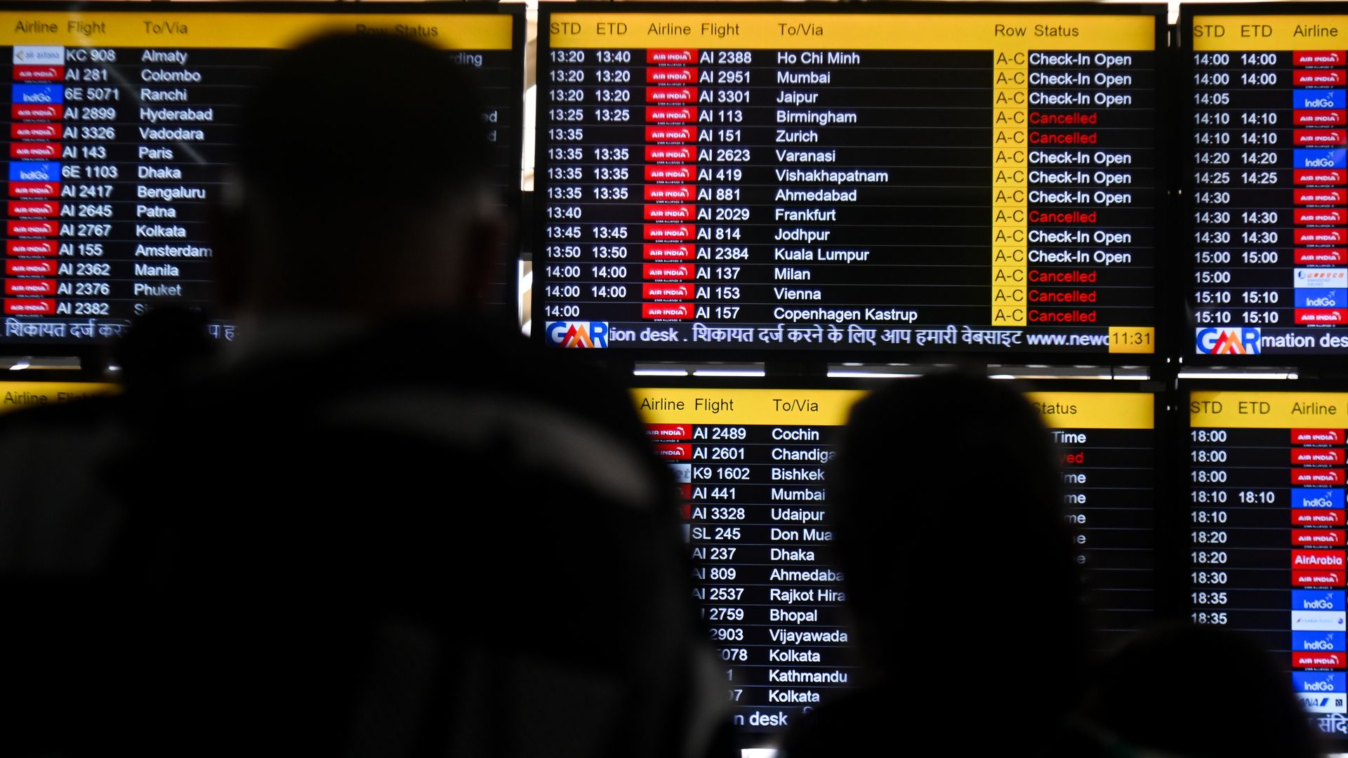 Passengers view airport flight screens with many cancellations