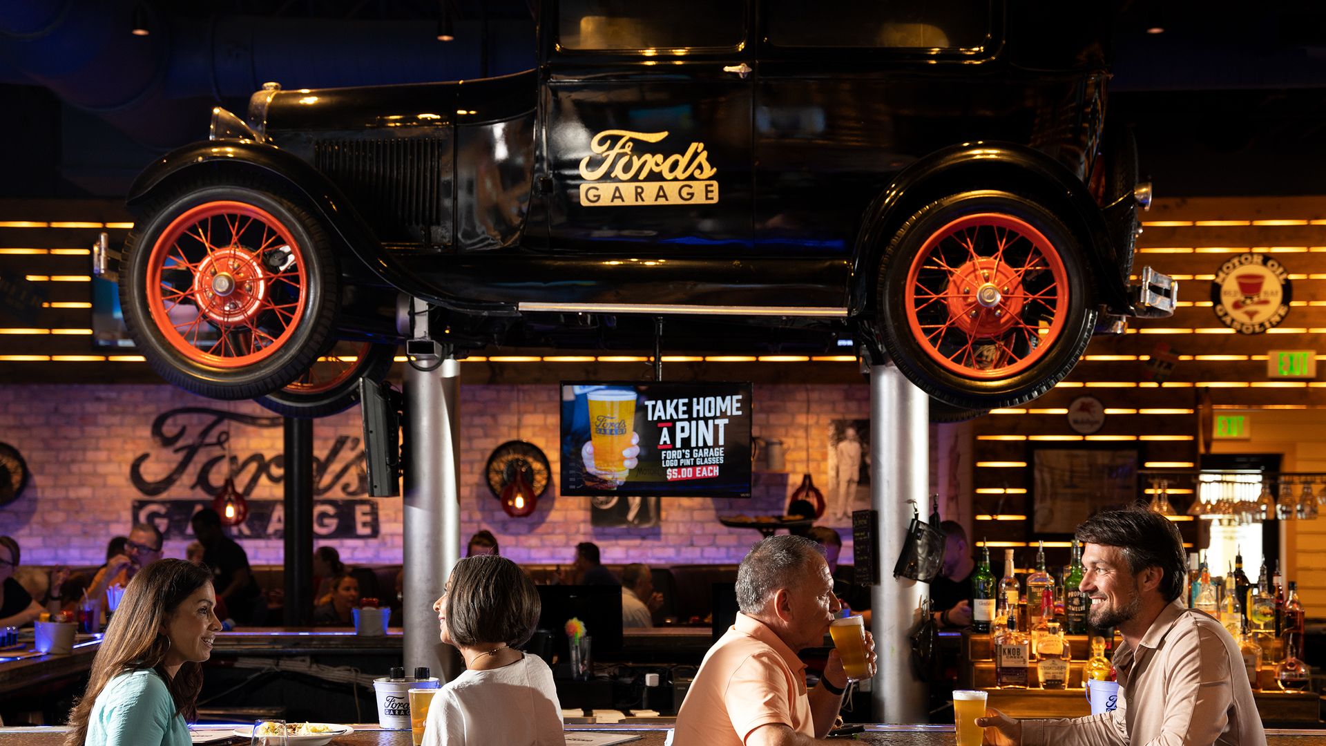 A restaurant bar with an old timey car over it 