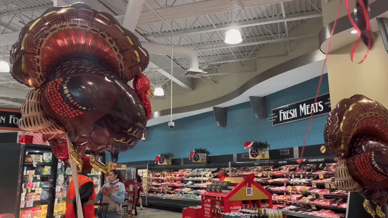 Turkey balloons sway in the meat section of Harris Teeter. 
