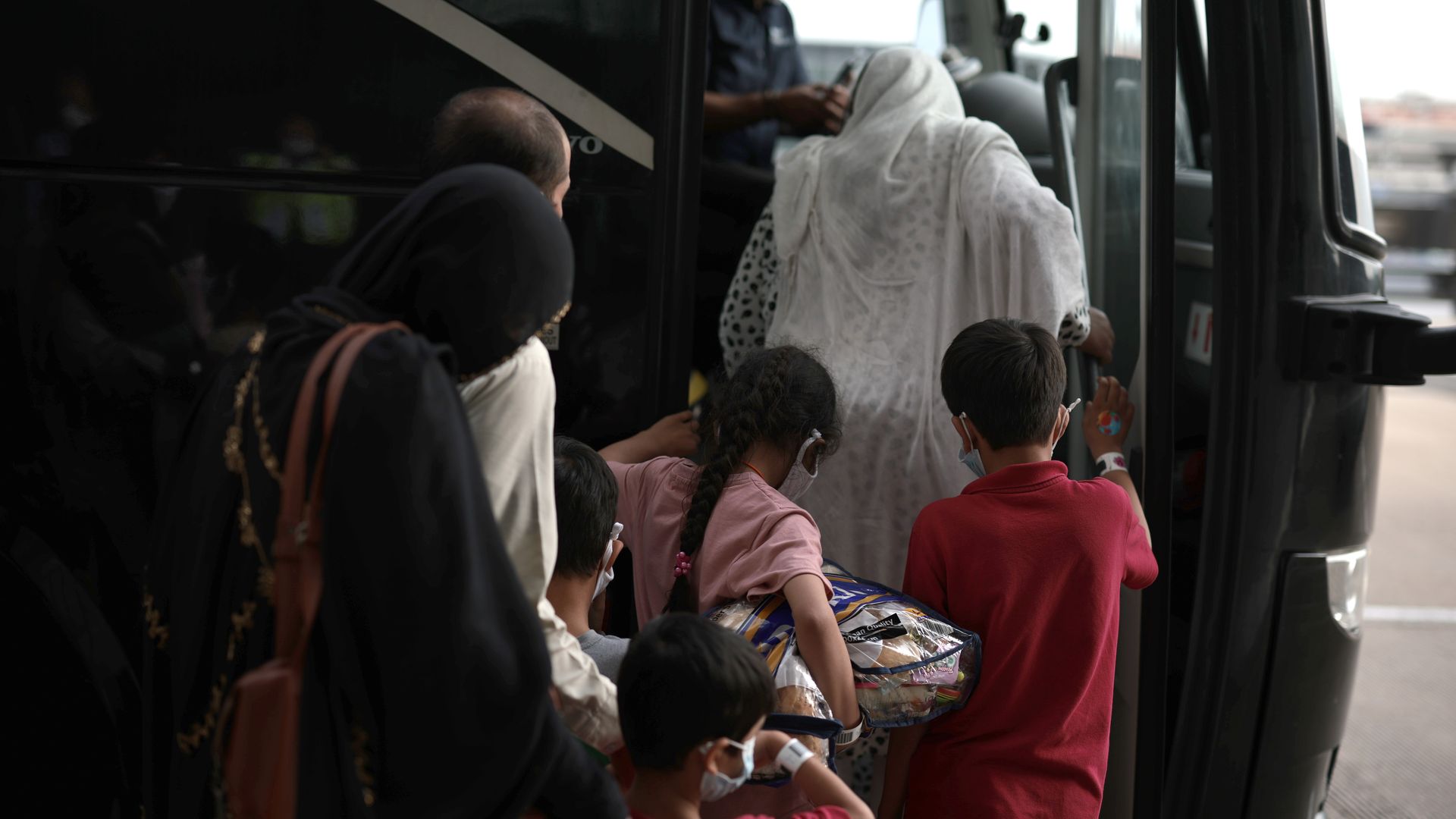 A family boards a bus at Dulles International Airport that will take them to a refugee processing center after being evacuated from Kabul 