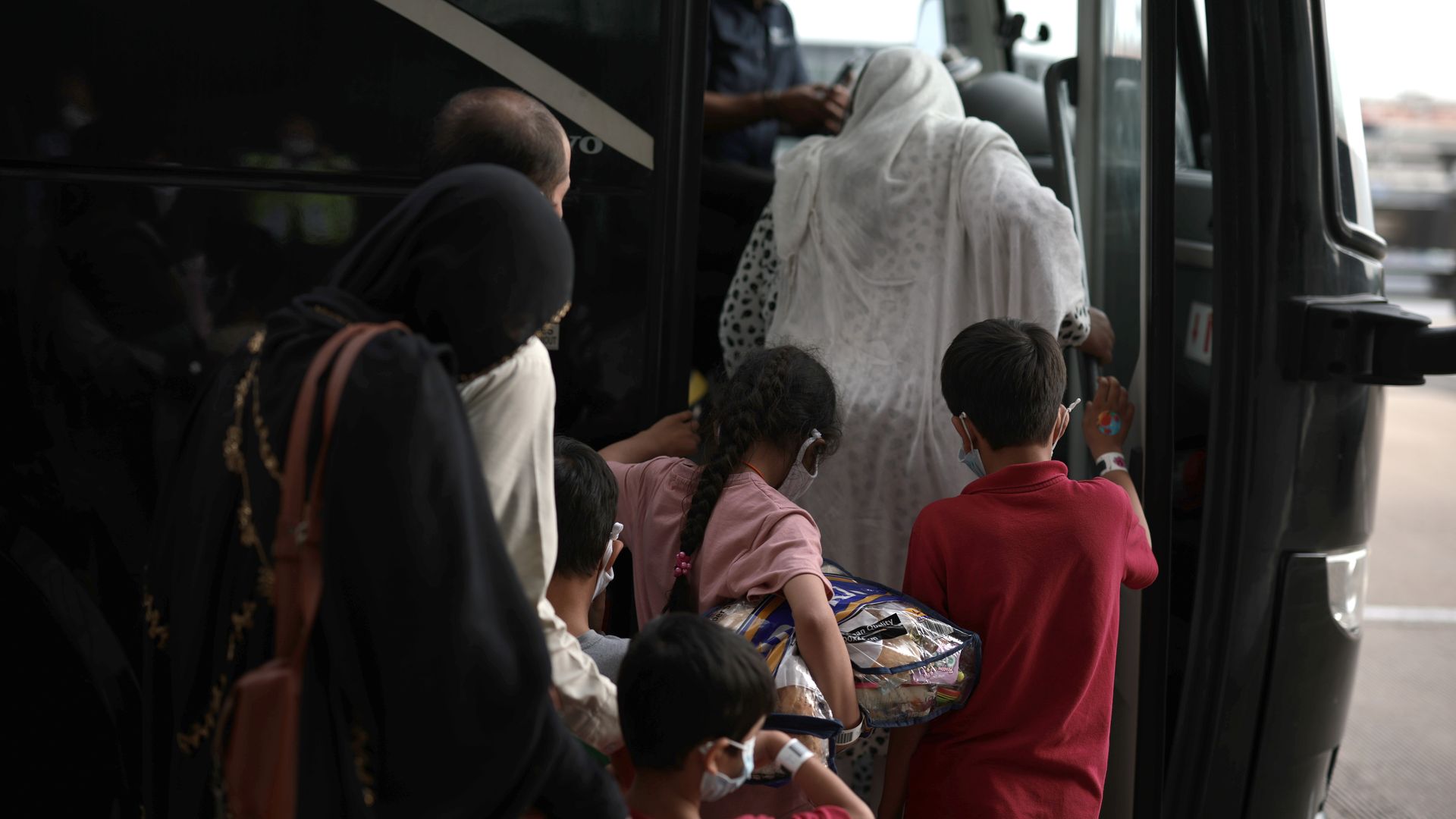 A family boards a bus at Dulles International Airport that will take them to a refugee processing center after being evacuated from Kabul