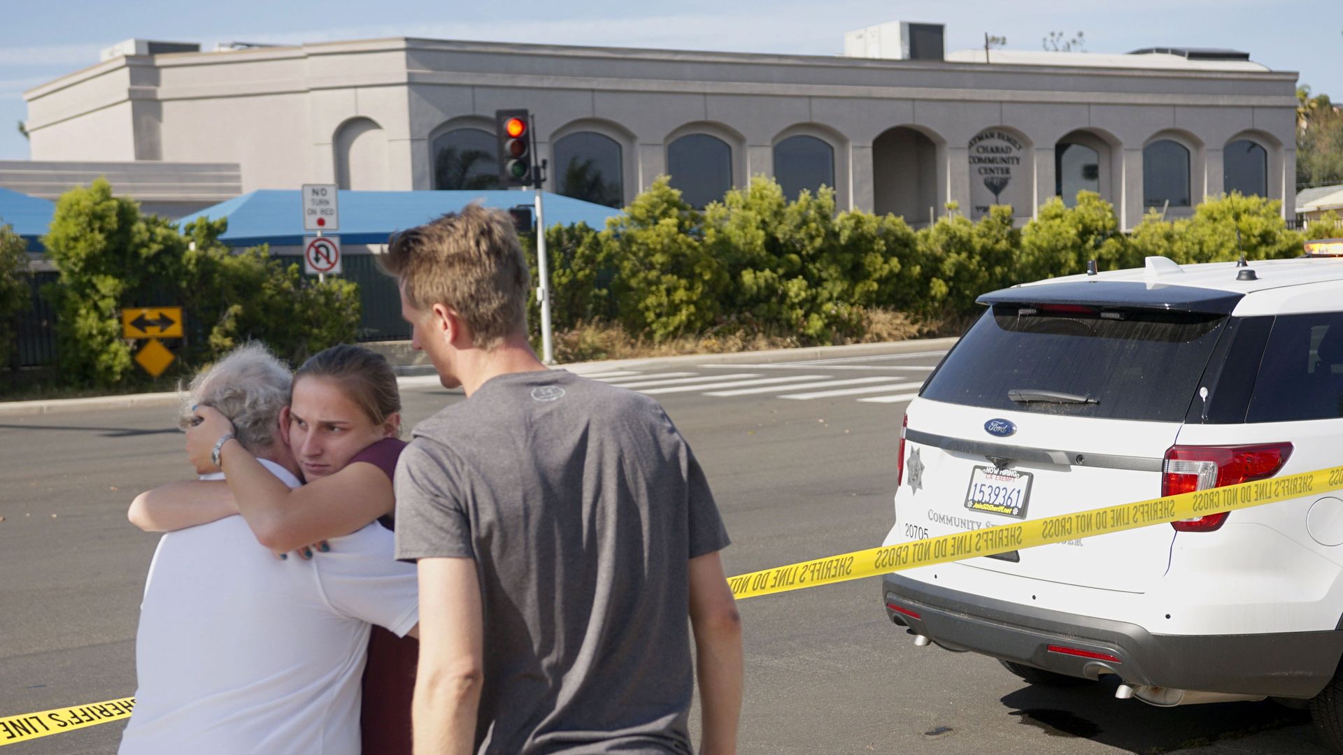 People hug next to police tape across the street from the Chabad of Poway Synagogue after a shooting on Saturday.