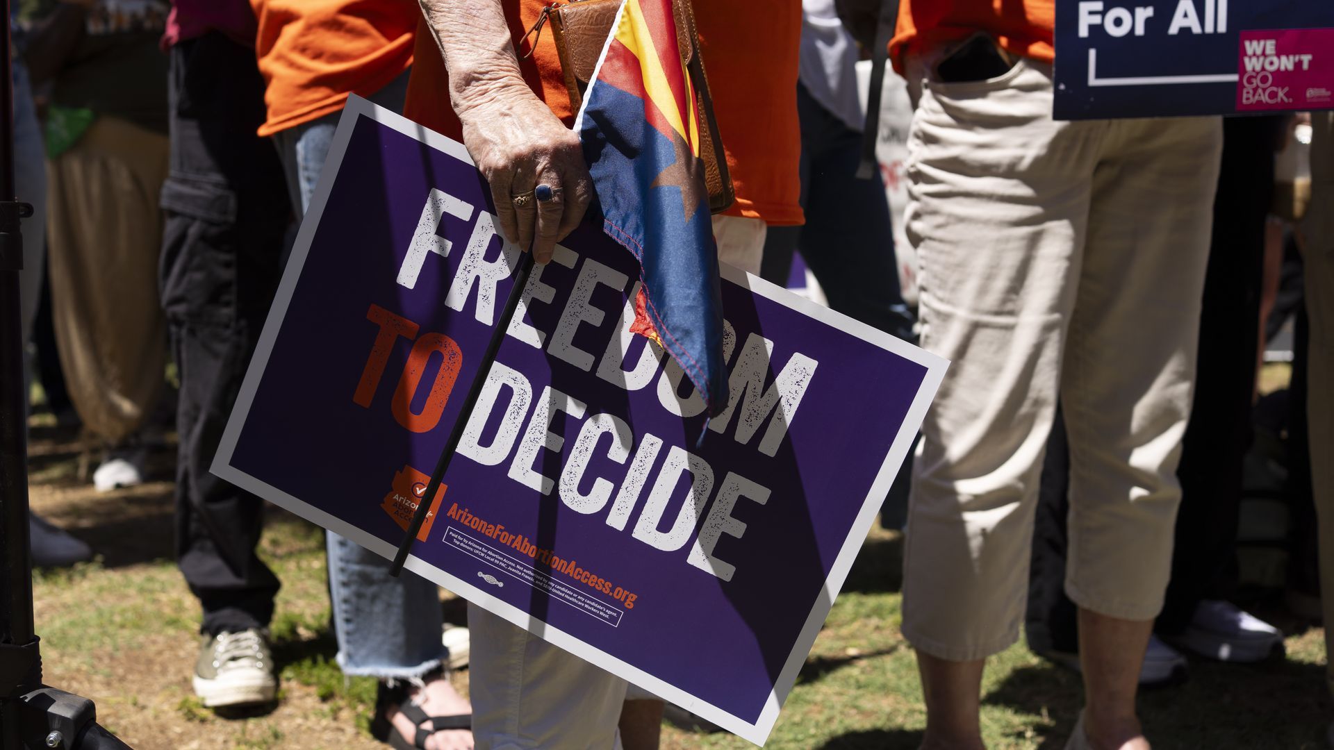 A protester holds a small Arizona flag and a sign that reads "freedom to decide."