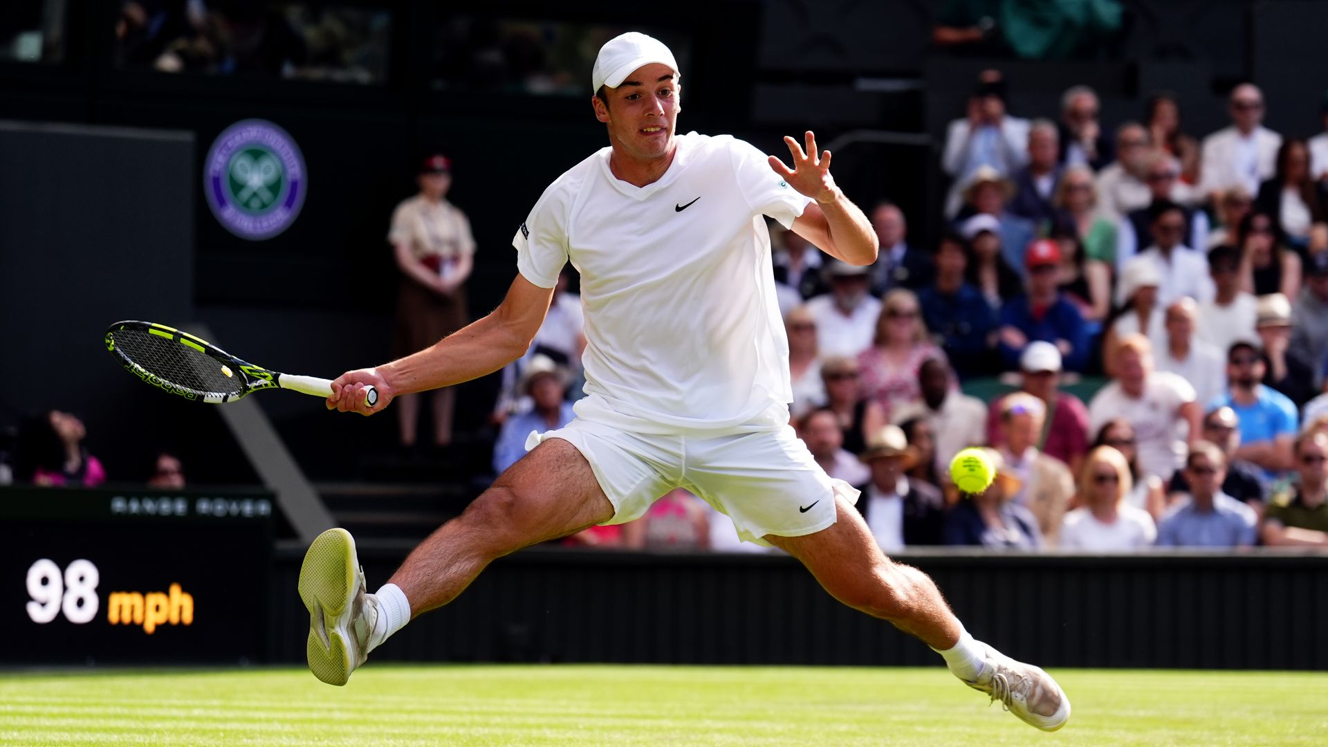 A tennis player stretches to hit the ball on the court.