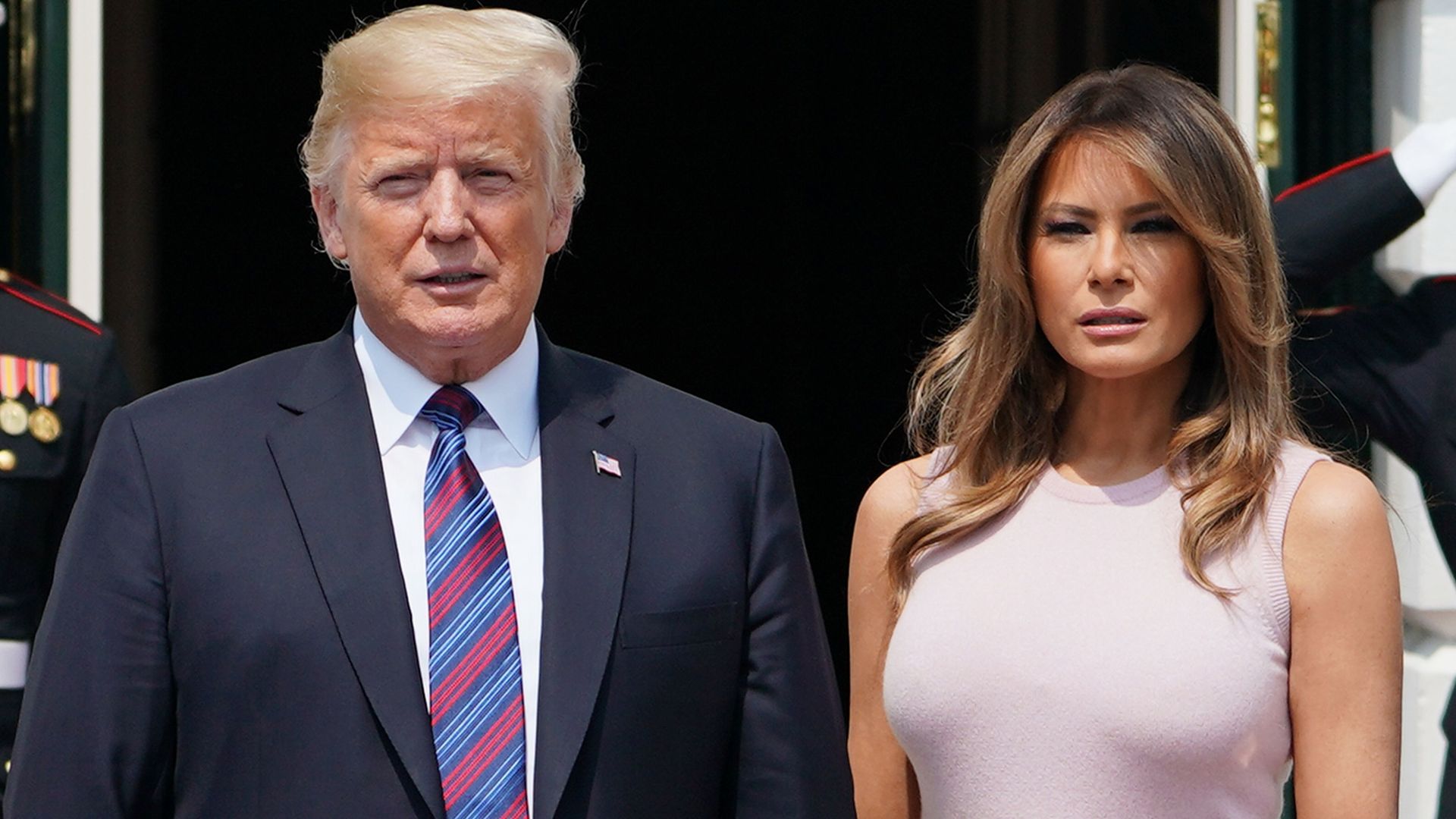 Melania Trump and Donald Trump standing side by side outside of the White House with matching serious, open-mouthed looks on their faces