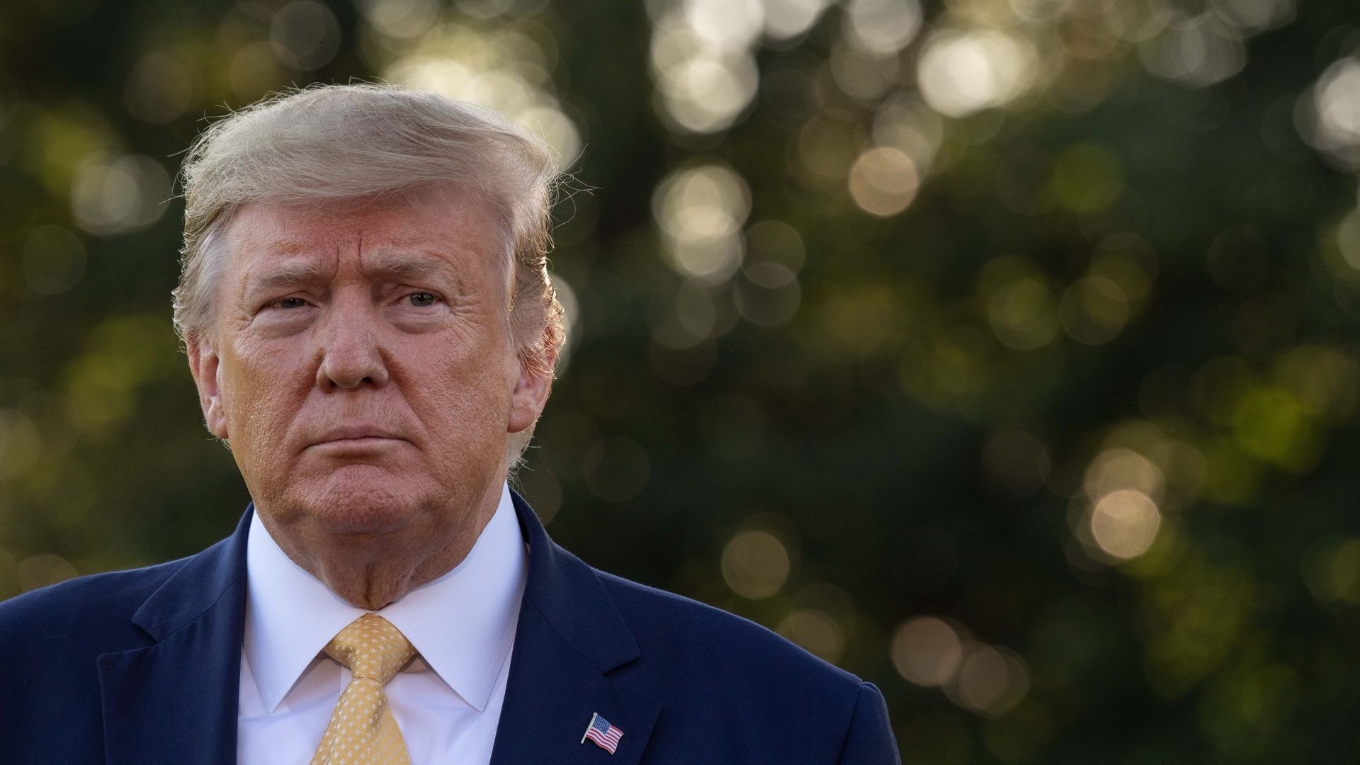 A headshot of Trump outside, not smiling, looking directly at the camera.