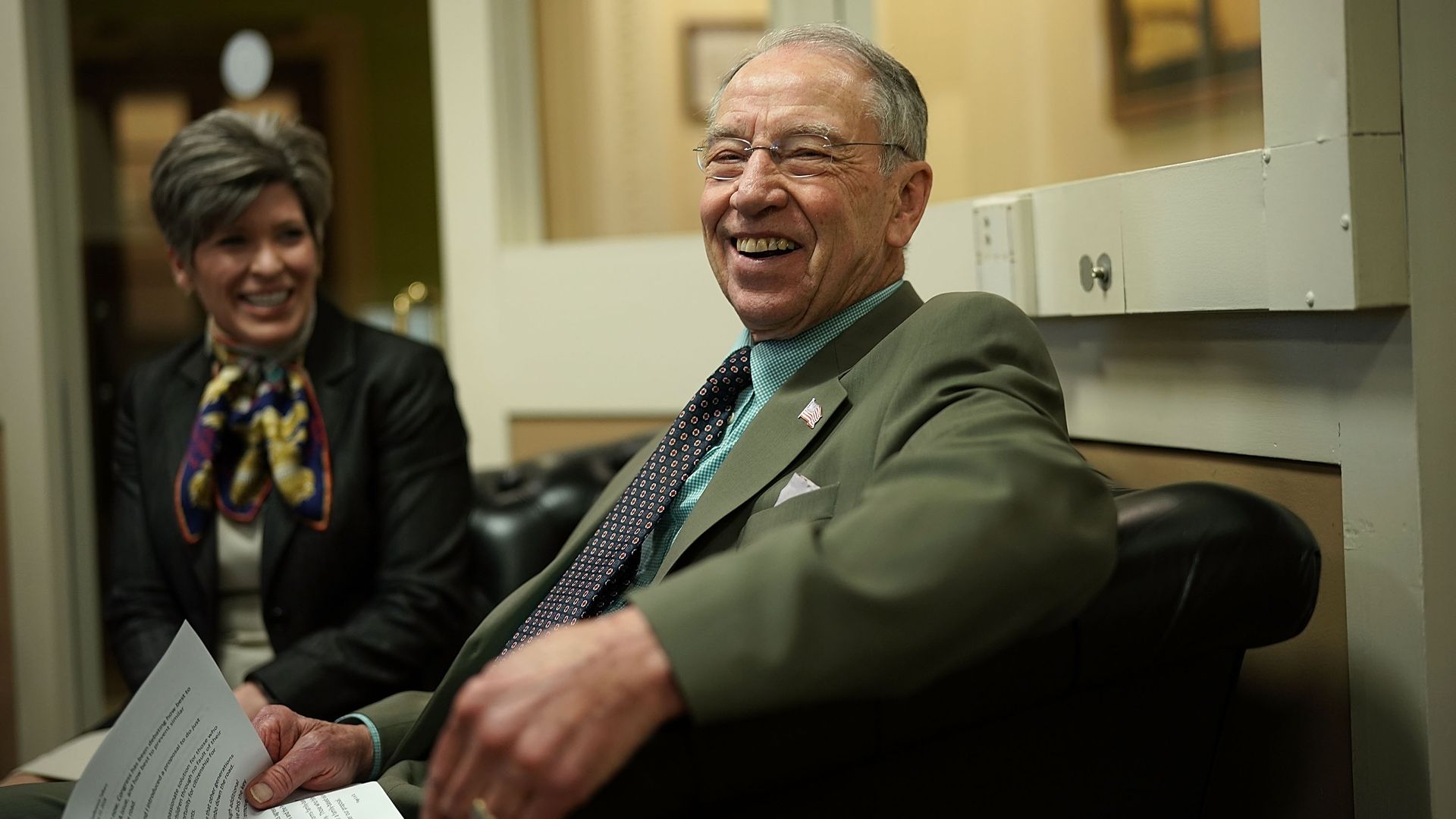Chuck Grassley sitting with papers and laughing