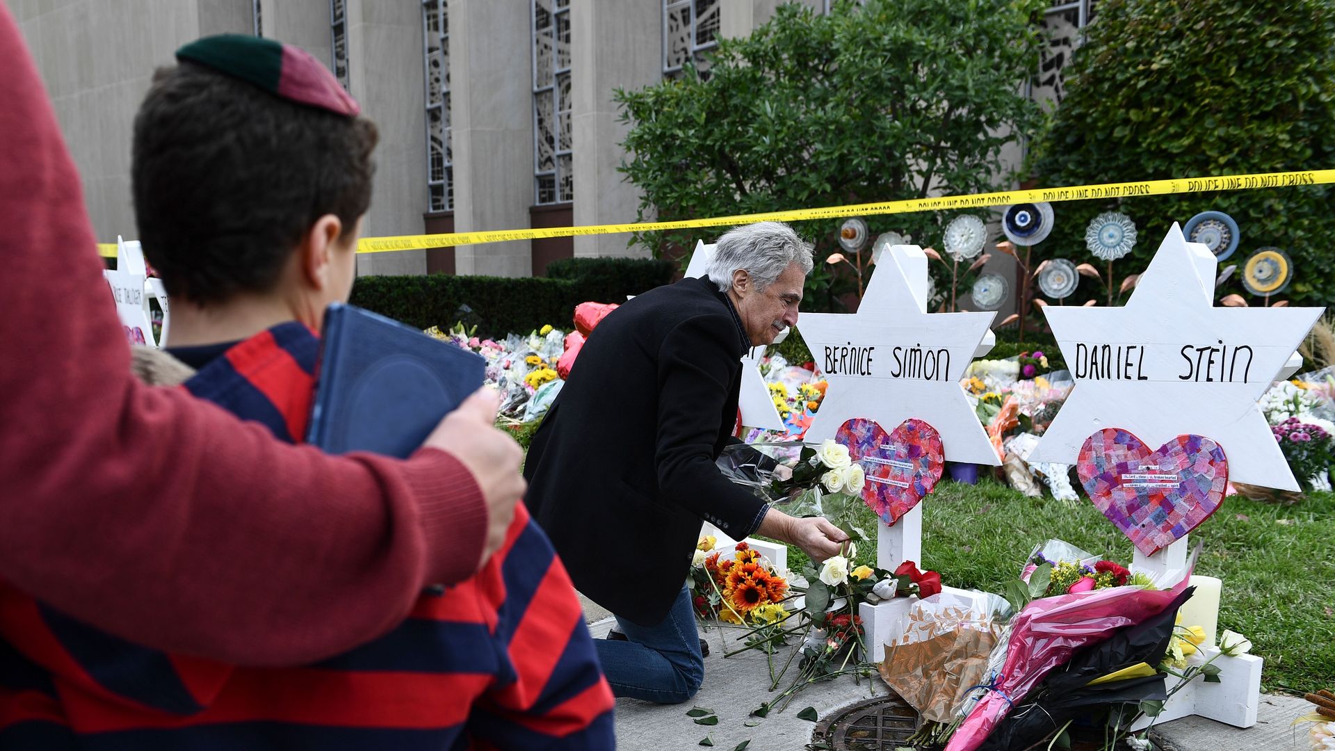 In this image, a man lays flowers at memorials for shooting victims, outside.