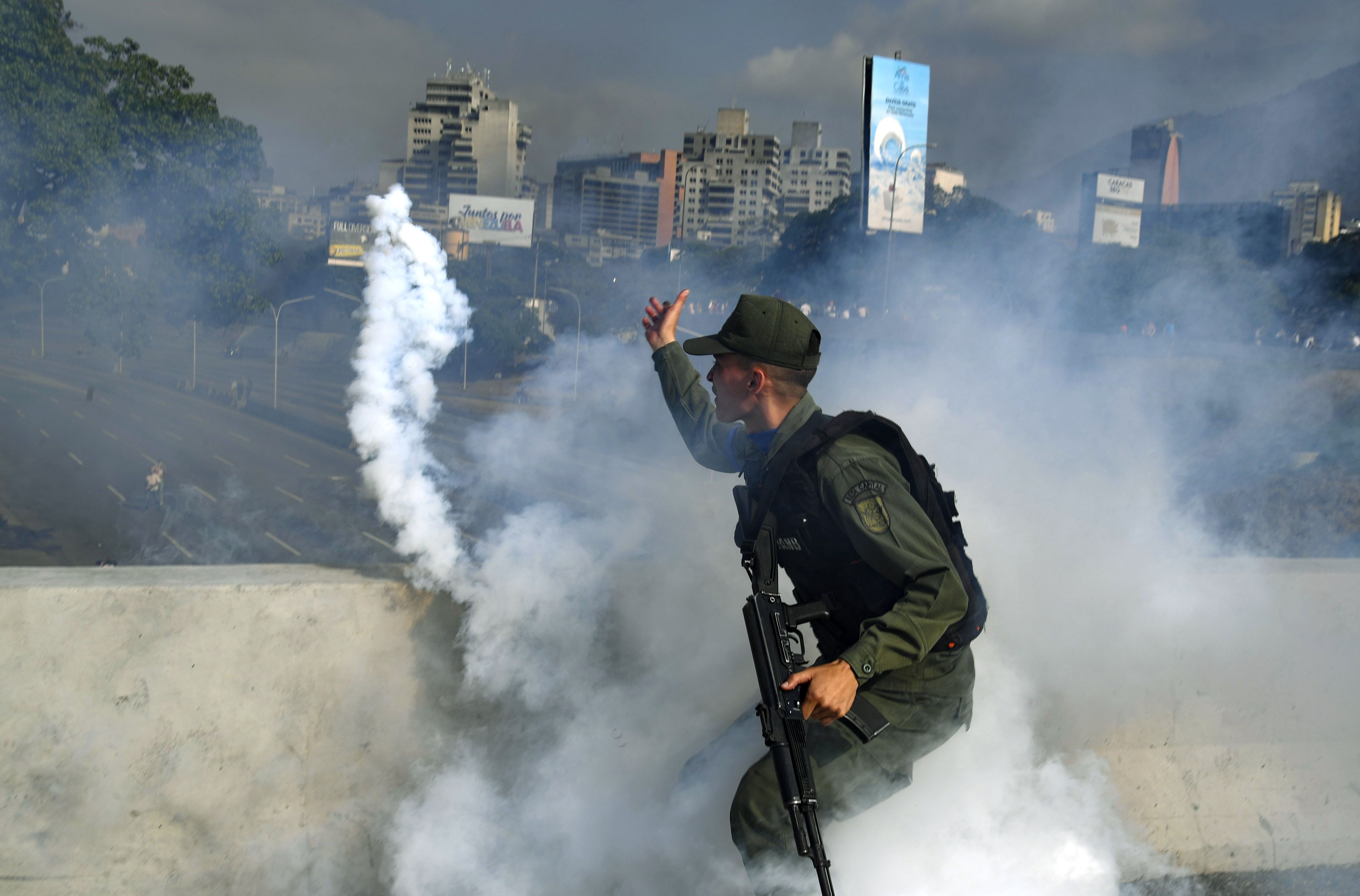A member of the Bolivarian National Guard supporting Venezuelan opposition leader Juan Guaido throws a tear gas canister.