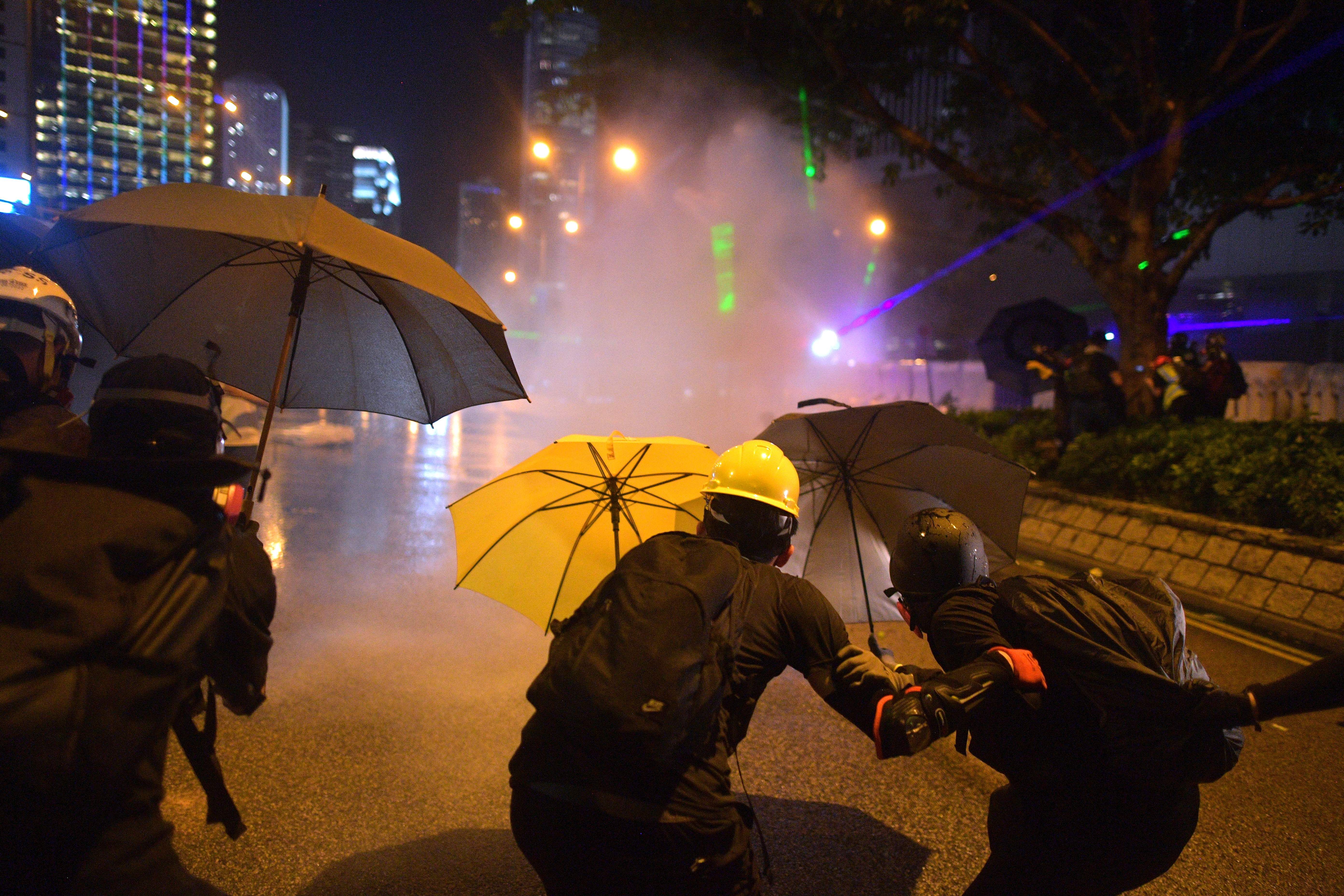  Protesters protect themselves after police fired water cannon toward them after the group occupied a main road in the Admiralty area in Hong Kong on September 28