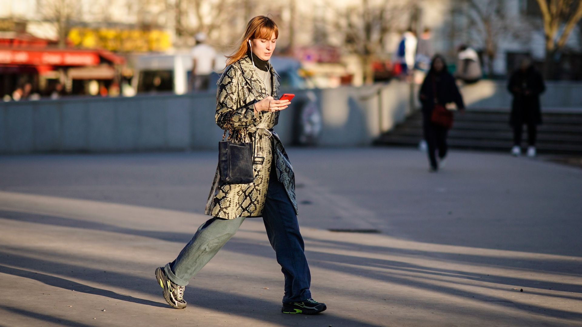 Photo of a woman walking outside looking at a phone