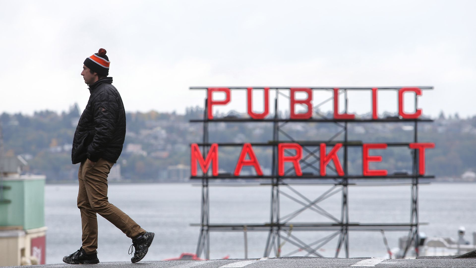 A solitary person walks in front of the Public Market sign in downtown Seattle.
