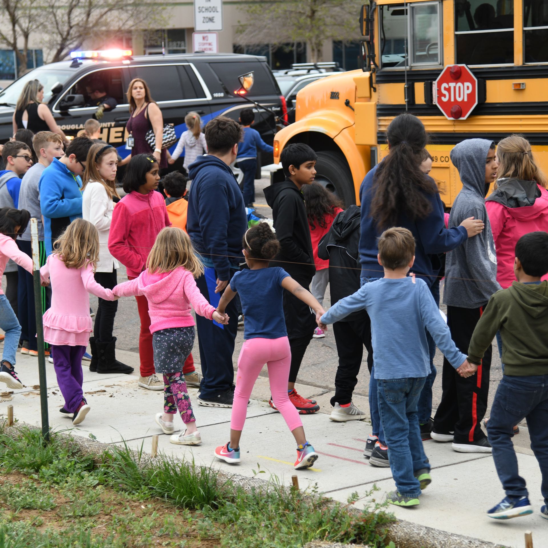 Students escorted school bus in front of STEM School Highlands Ranch after a shooting. 