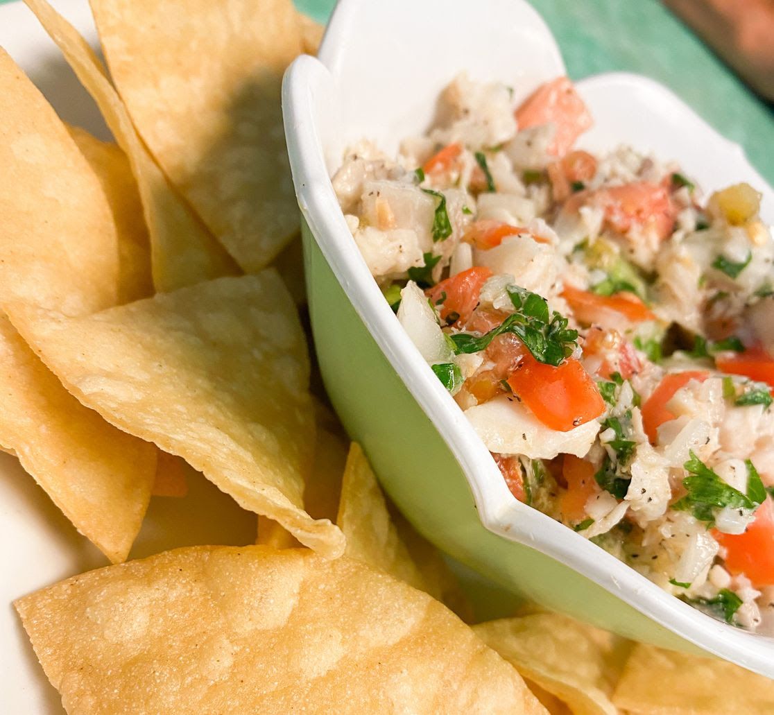 A bowl of fish and veggies served with corn chips.