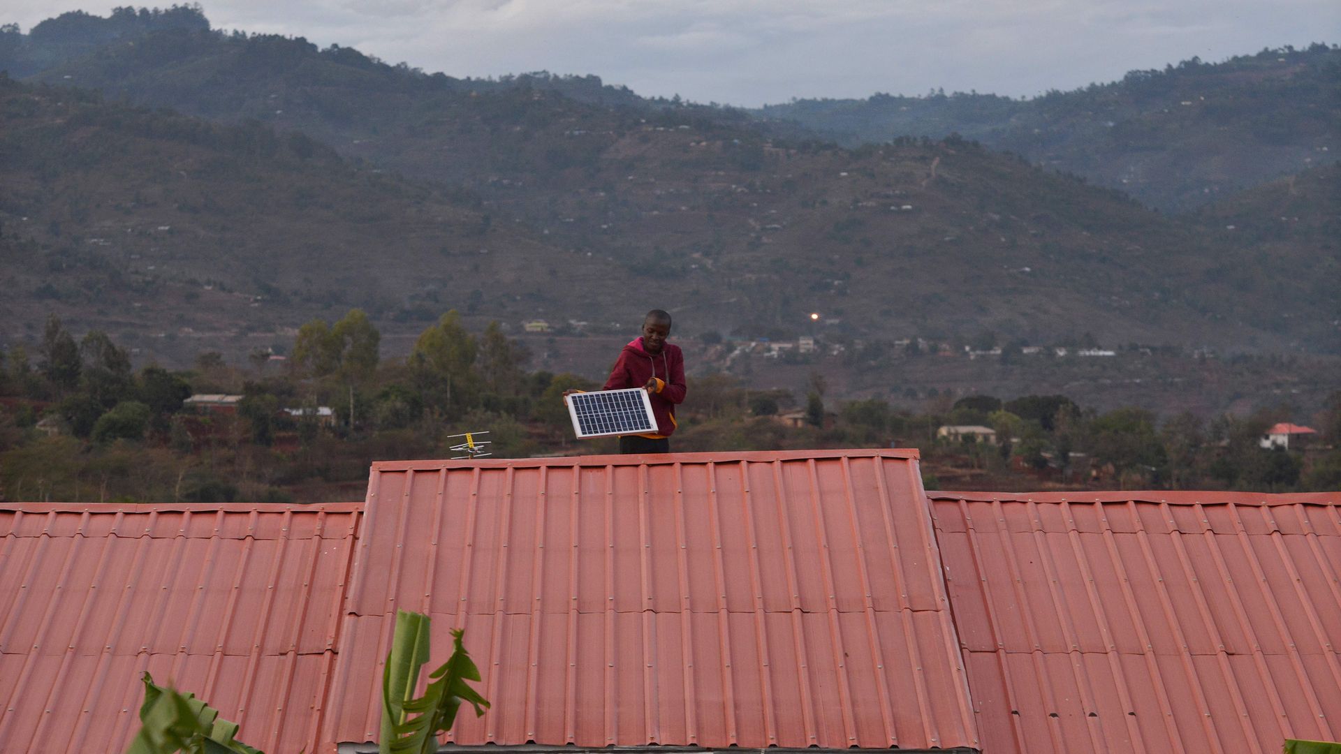 A man adjusts a solar panel on his roof at dusk in the villqge of Kwa-Mutisya in Machakos county, some 100 kilometres southeast of Nairobi, on November 16, 2016. 
