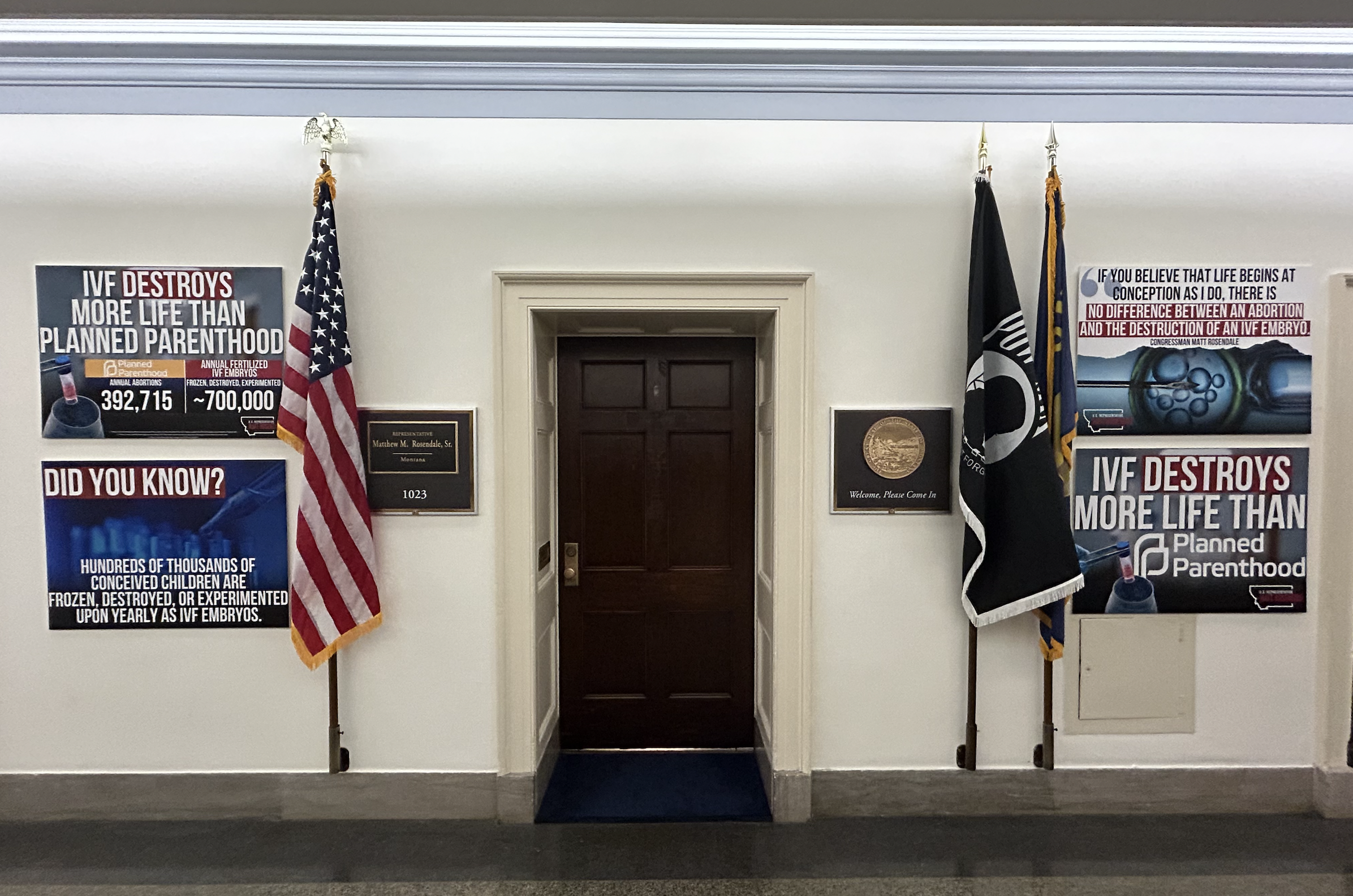 Rep. Matt Rosendale's office in the Longworth House Office Building with flags and anti-IVF signs on either side.