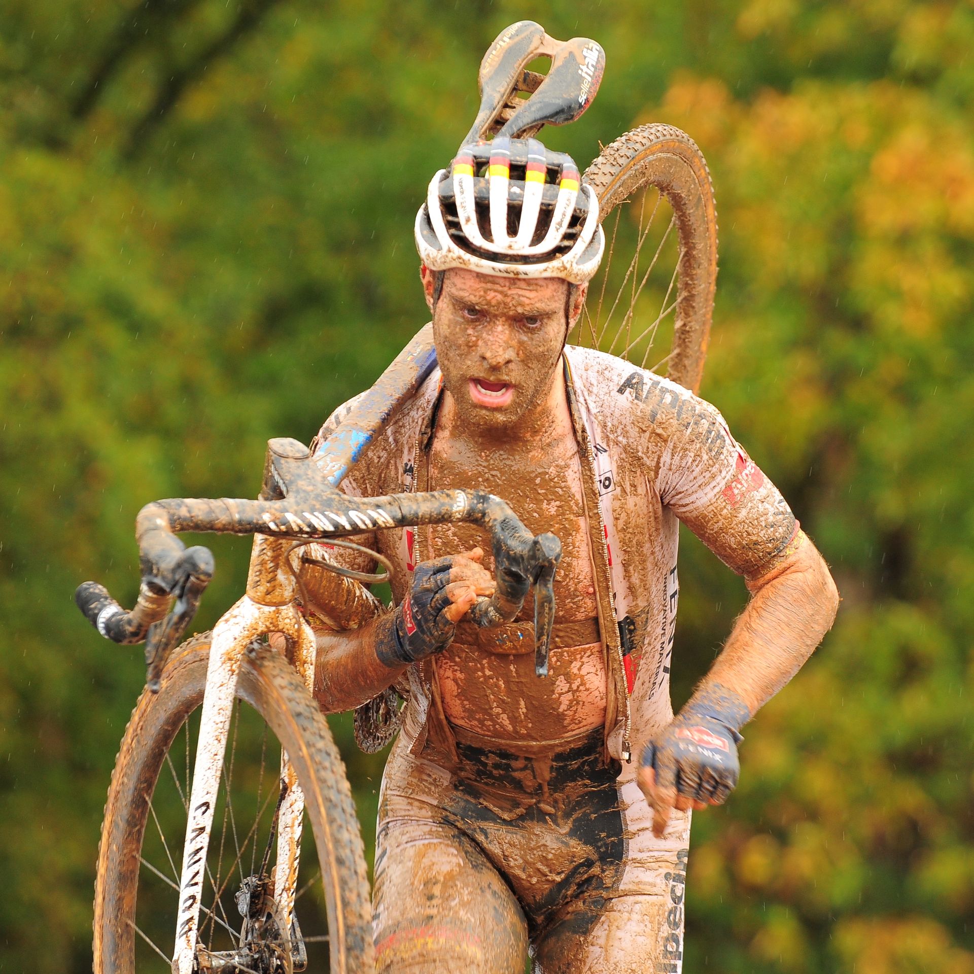 A muddy cyclist climbs stairs before riding down the other side. 