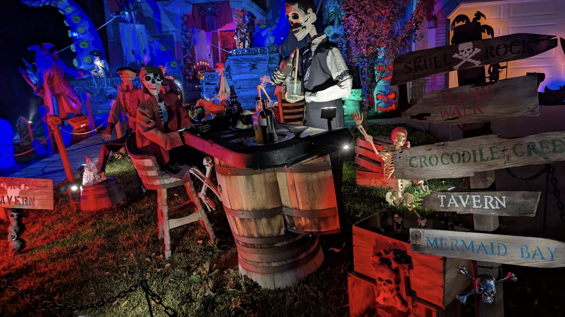 Halloween decorations depict a pirate town and ship on a residential lawn.