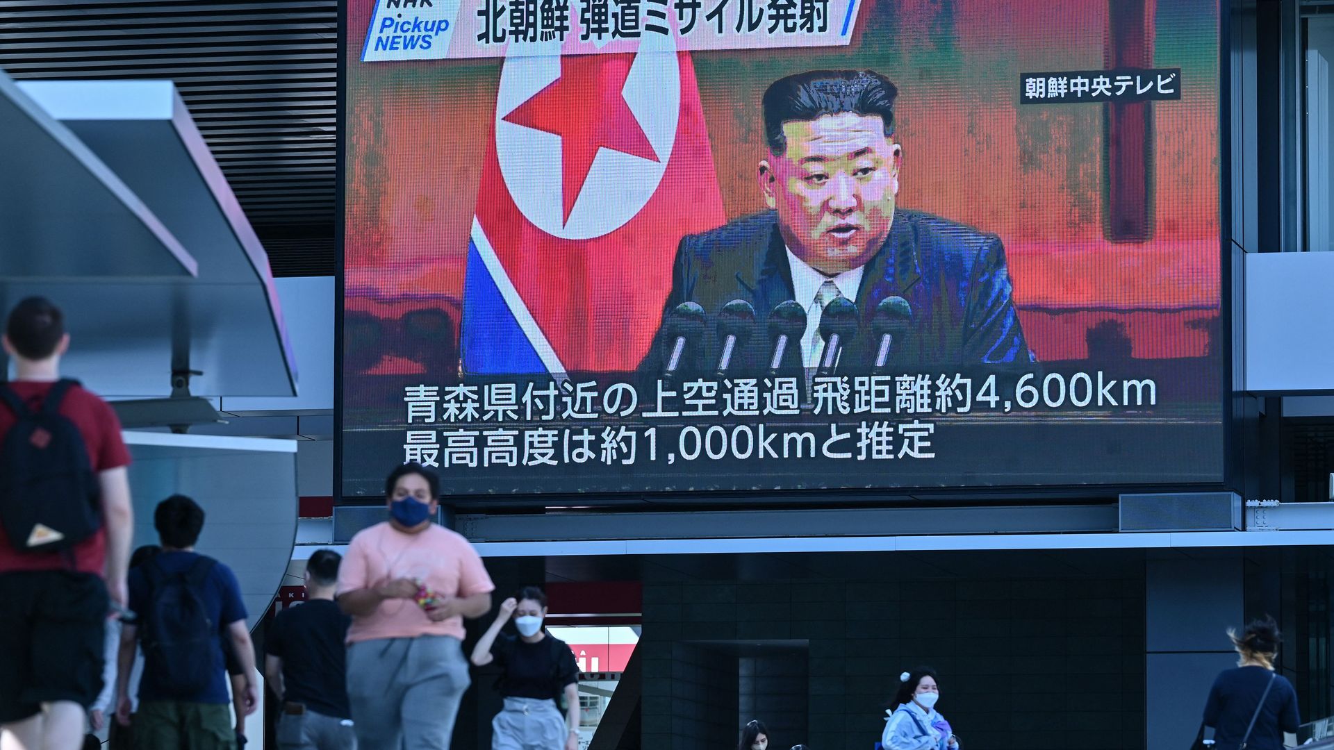 Pedestrians walk under a large creen showing images of North Korea's leader Kim Jong Un  in Tokyo on October 4, 2022, after North Korea launched a missile that flew over Japan.