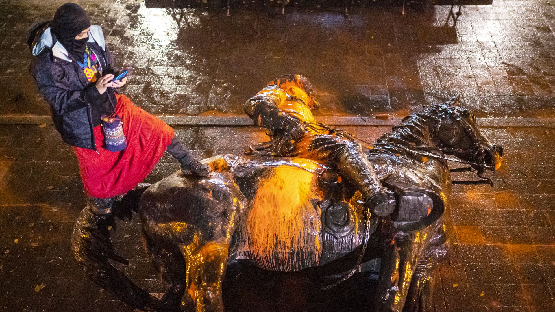 A protester stands over a toppled statue of President Theodore Roosevelt during an Indigenous Peoples Day of Rage protest on October 11, 2020 in Portland, Oregon.