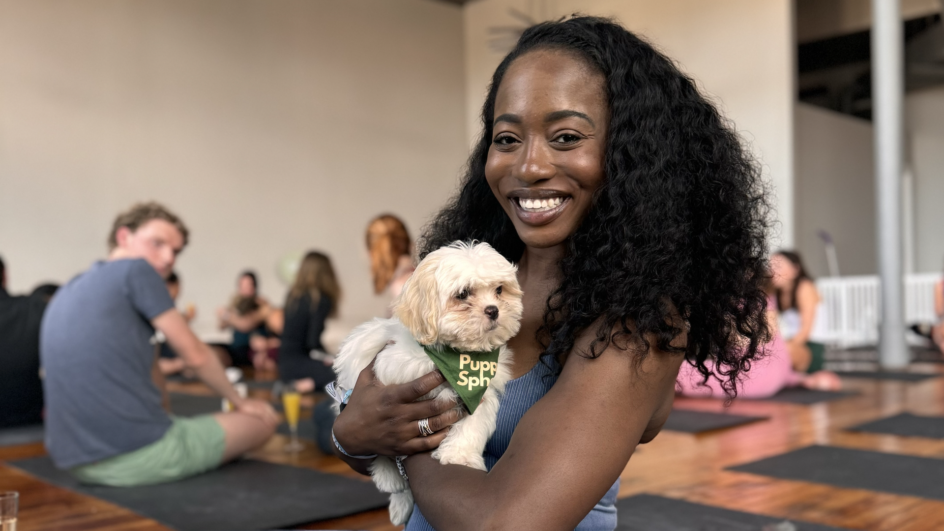 Photo of a woman holding a puppy while doing yoga 
