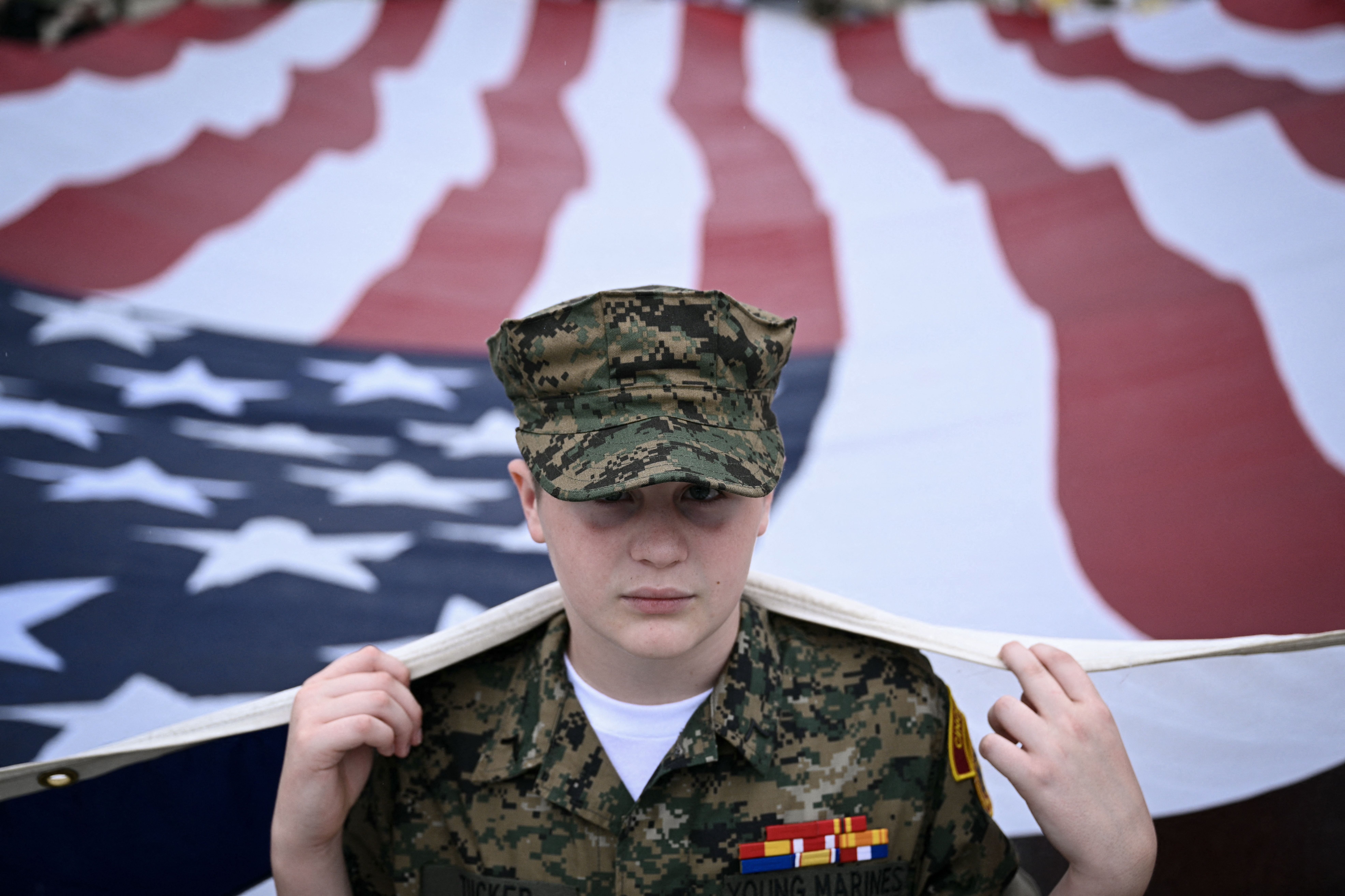A member of the "Young Marines" youth program helps carry a large American flag during the National Memorial Day Parade on Constitution Avenue in Washington, DC, May 25, 2026. (Photo by Brendan SMIALOWSKI / AFP via Getty Images)
