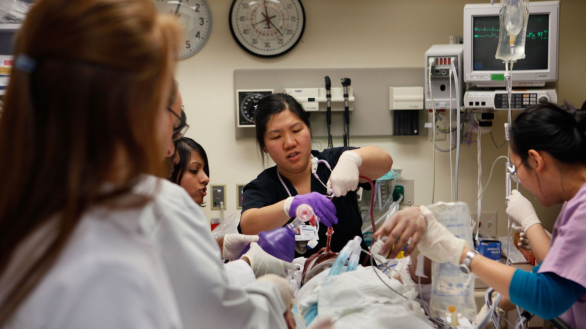 Doctors and nurses treat a patient in a hospital trauma room.