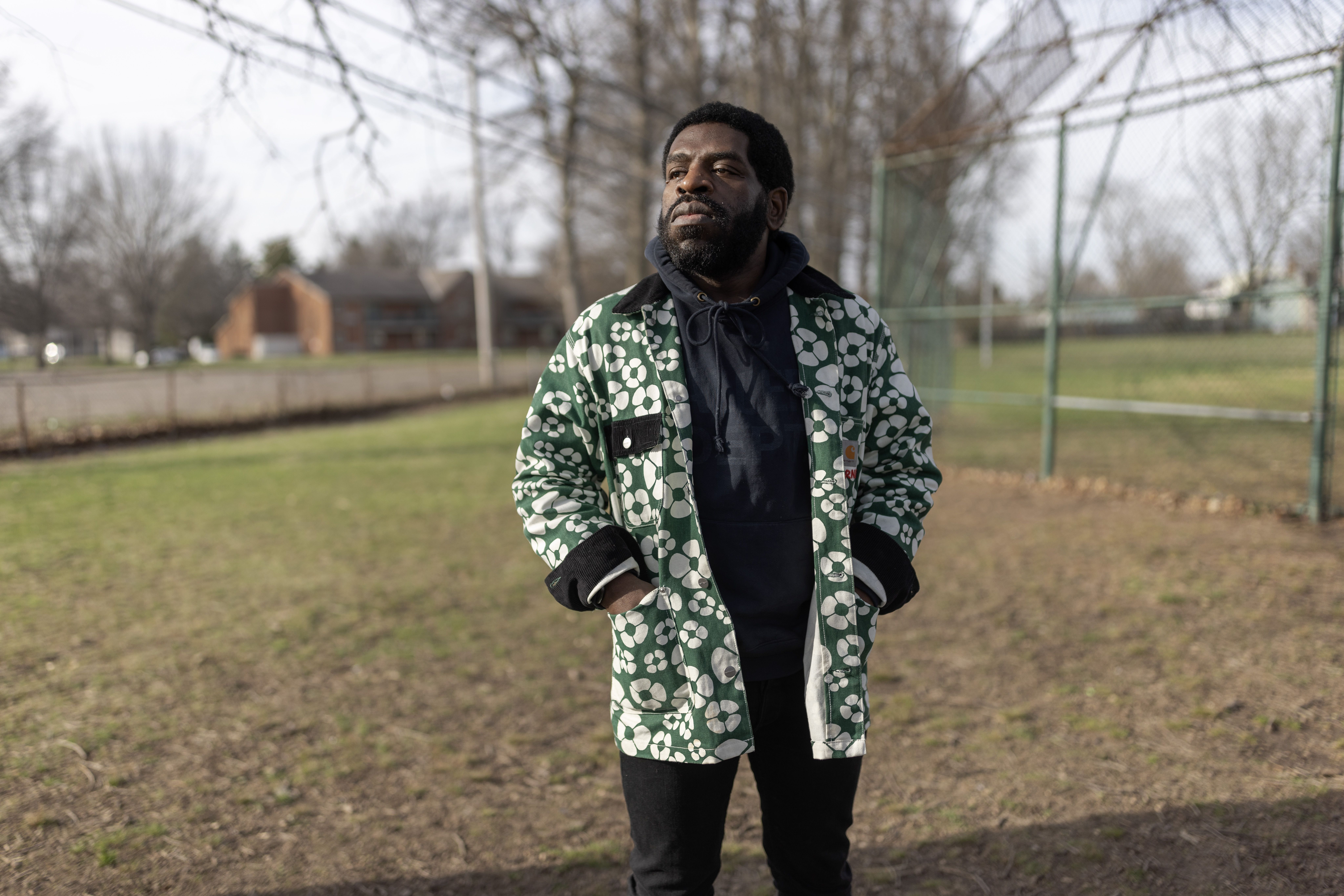 Hanif Abdurraqib stands on a field with hands in his pockets.