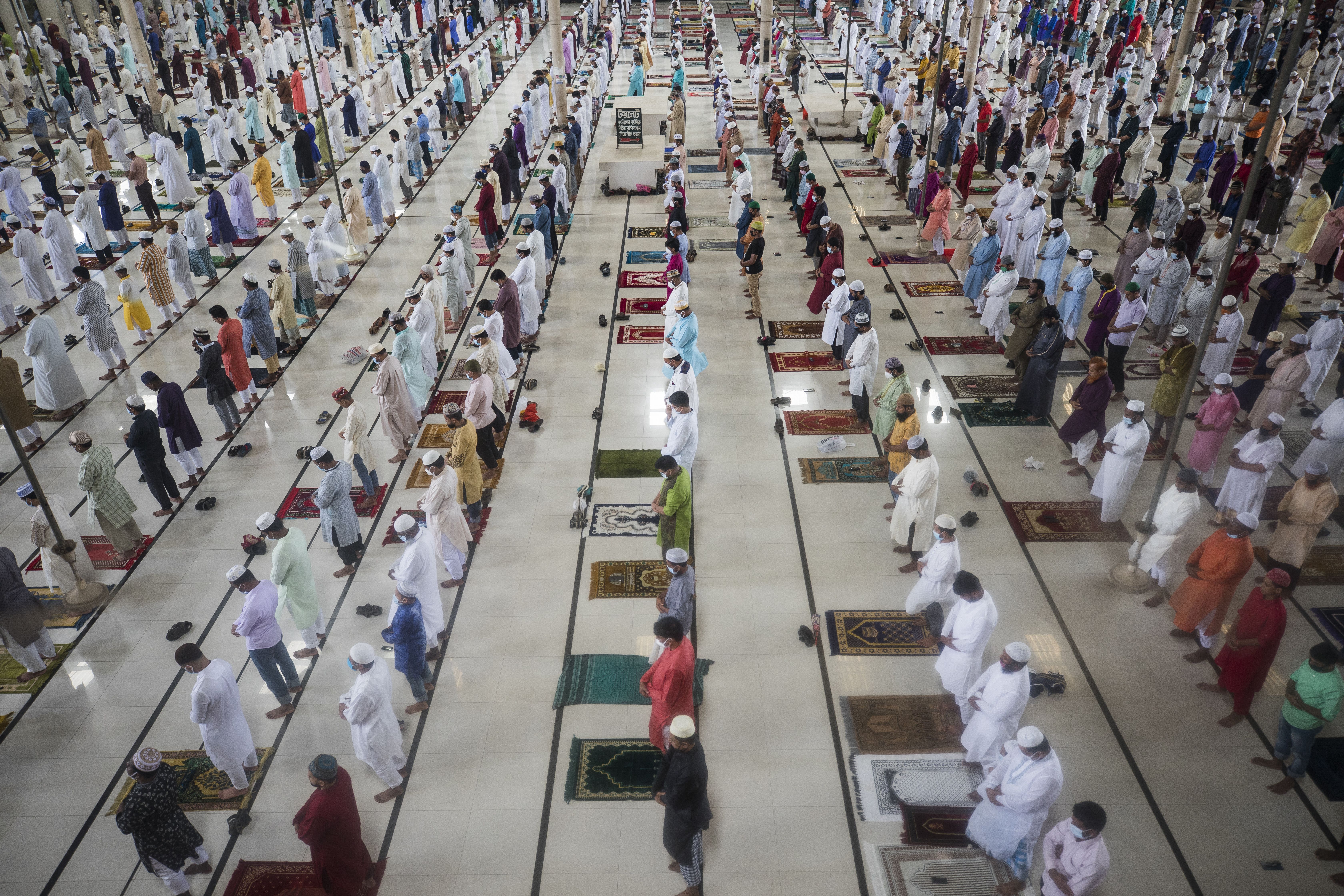 Rows of people stand in white clothing before prayer 