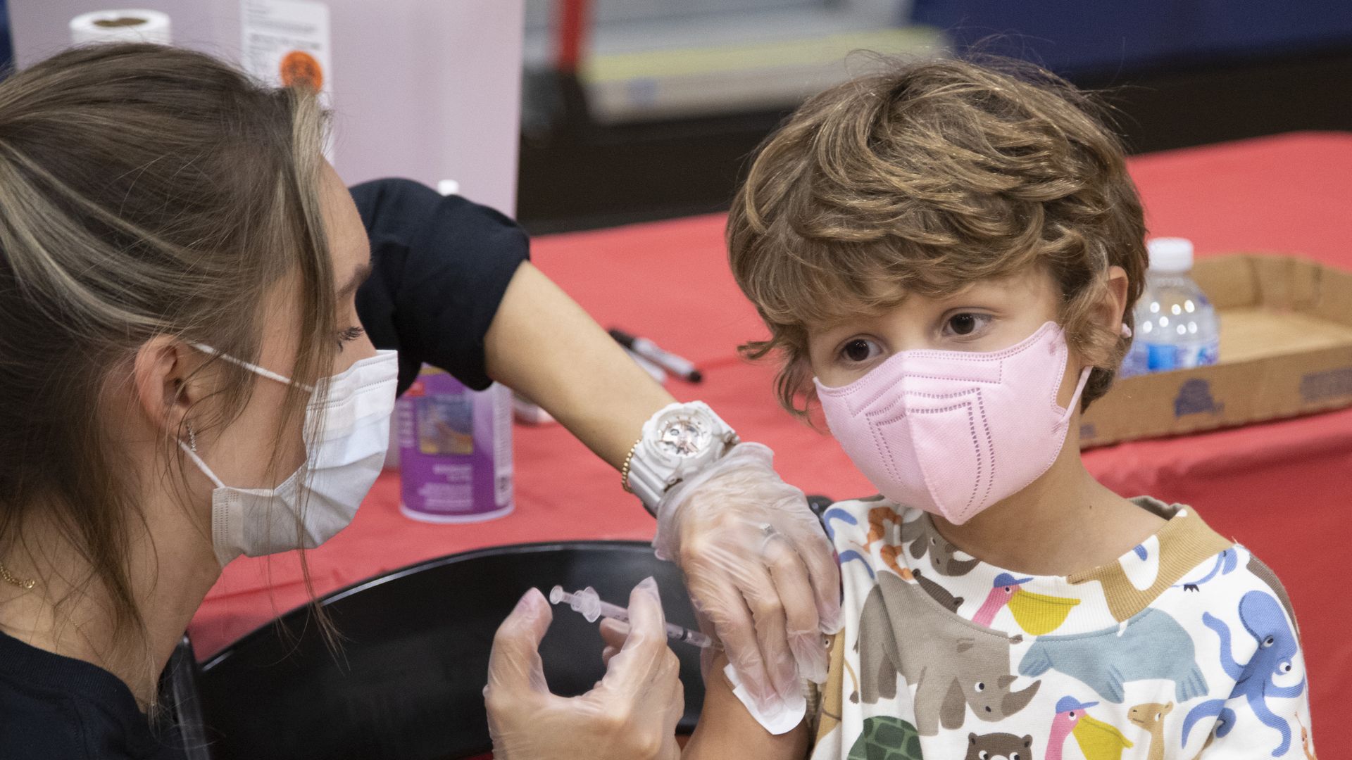 A 6-year-old child with a pink mask getting vaccinated