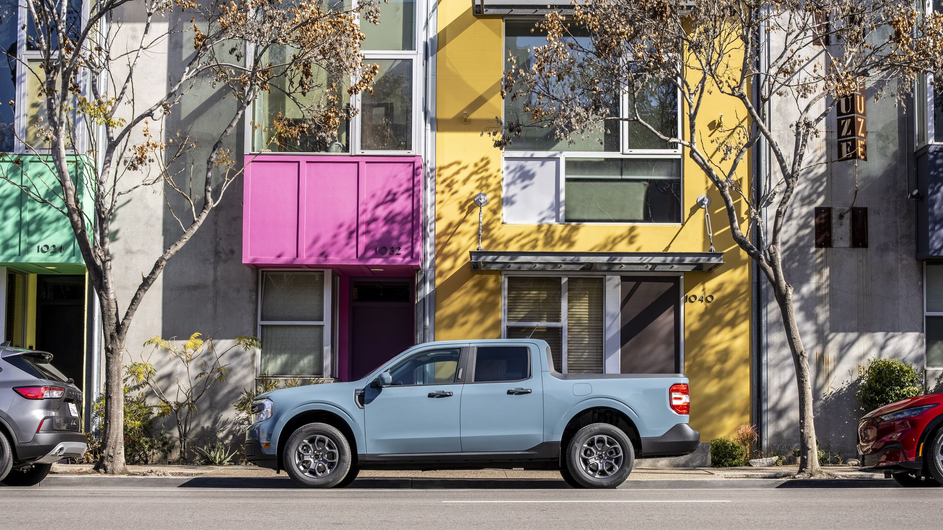 A light blue 2022 Ford Maverick pickup parked in front of a colorful building