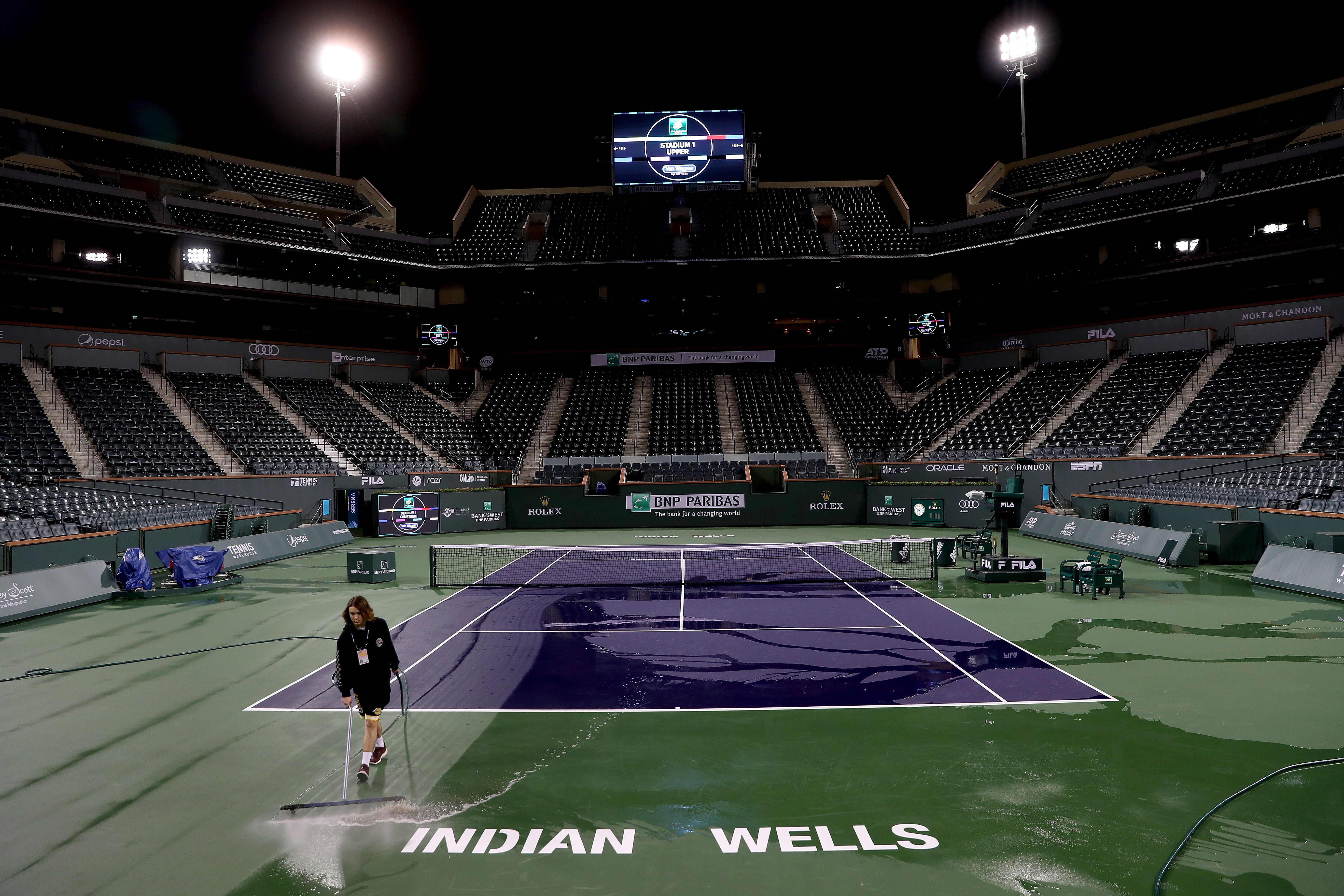 Worker sweeps tennis court